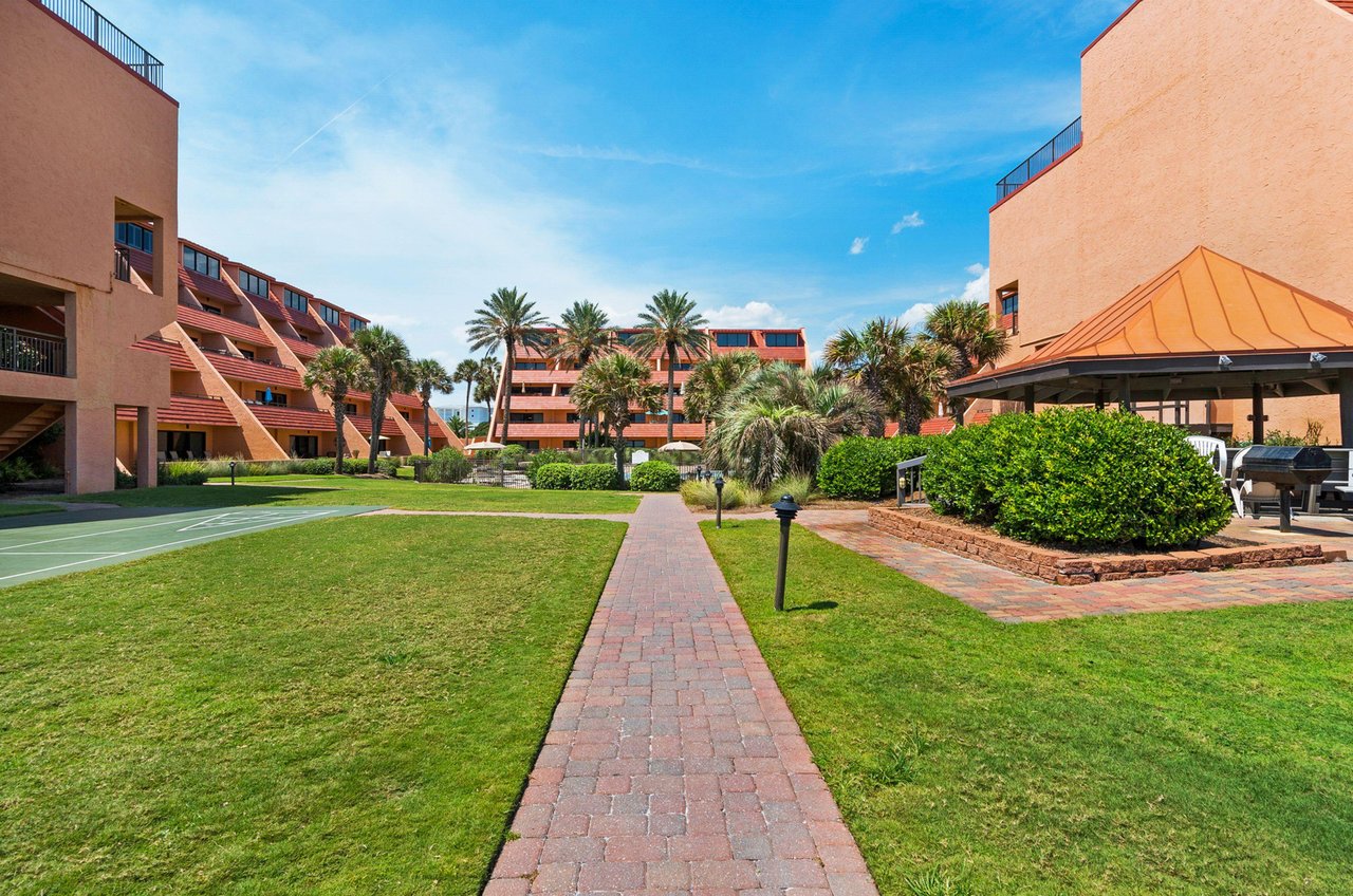 A shuffleboard court set among lush landscaping and brick paths provides guests a fun activity in the tropical setting.