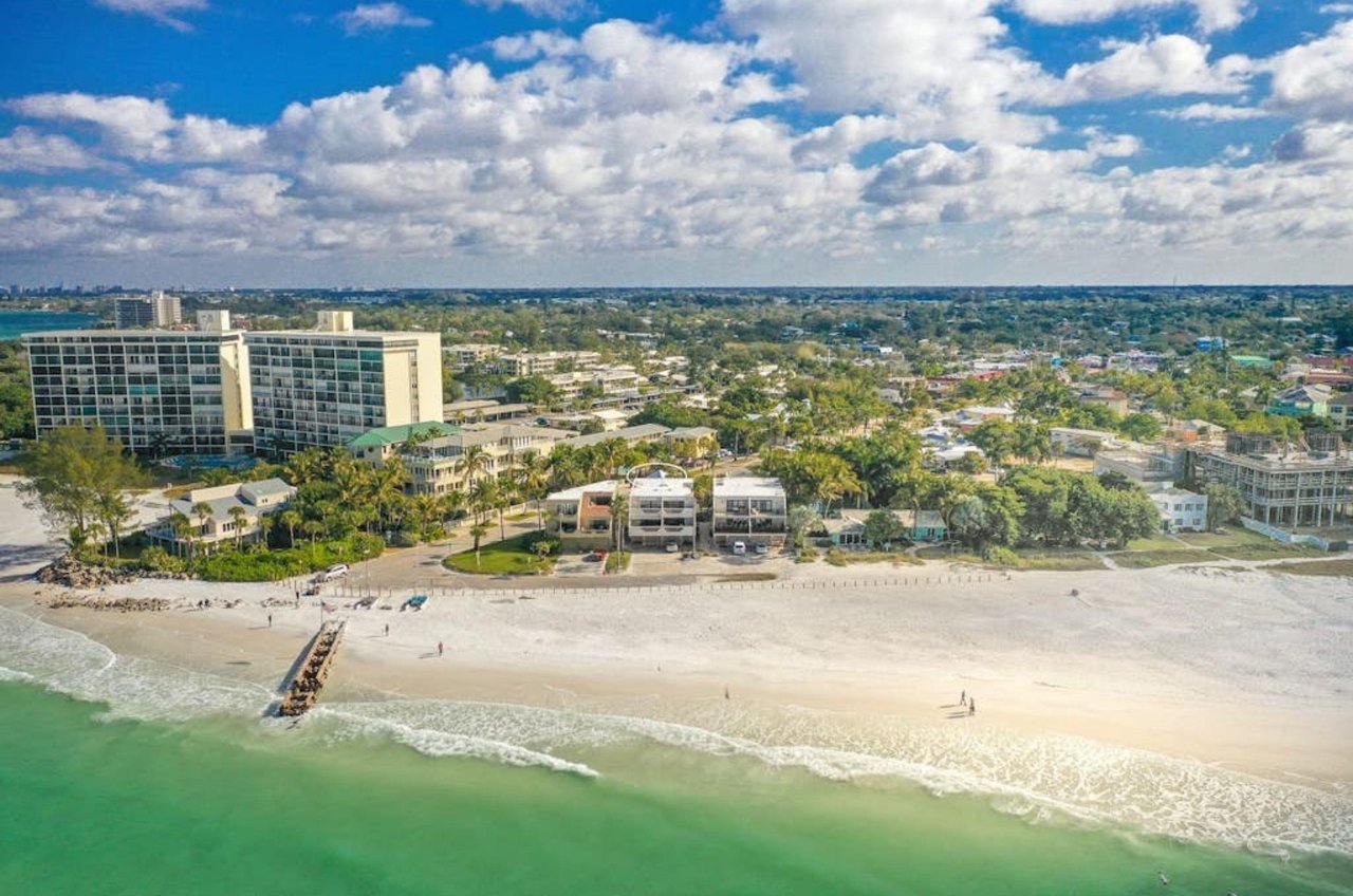 Birds eye view from the ocean of the beach and the green inland with rental homes in Siesta Key Florida