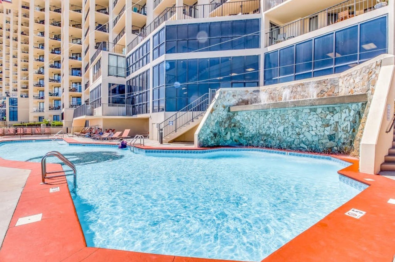 The outdoor swimming pool with a waterfall in front of Phoenix III in Orange Beach Alabama