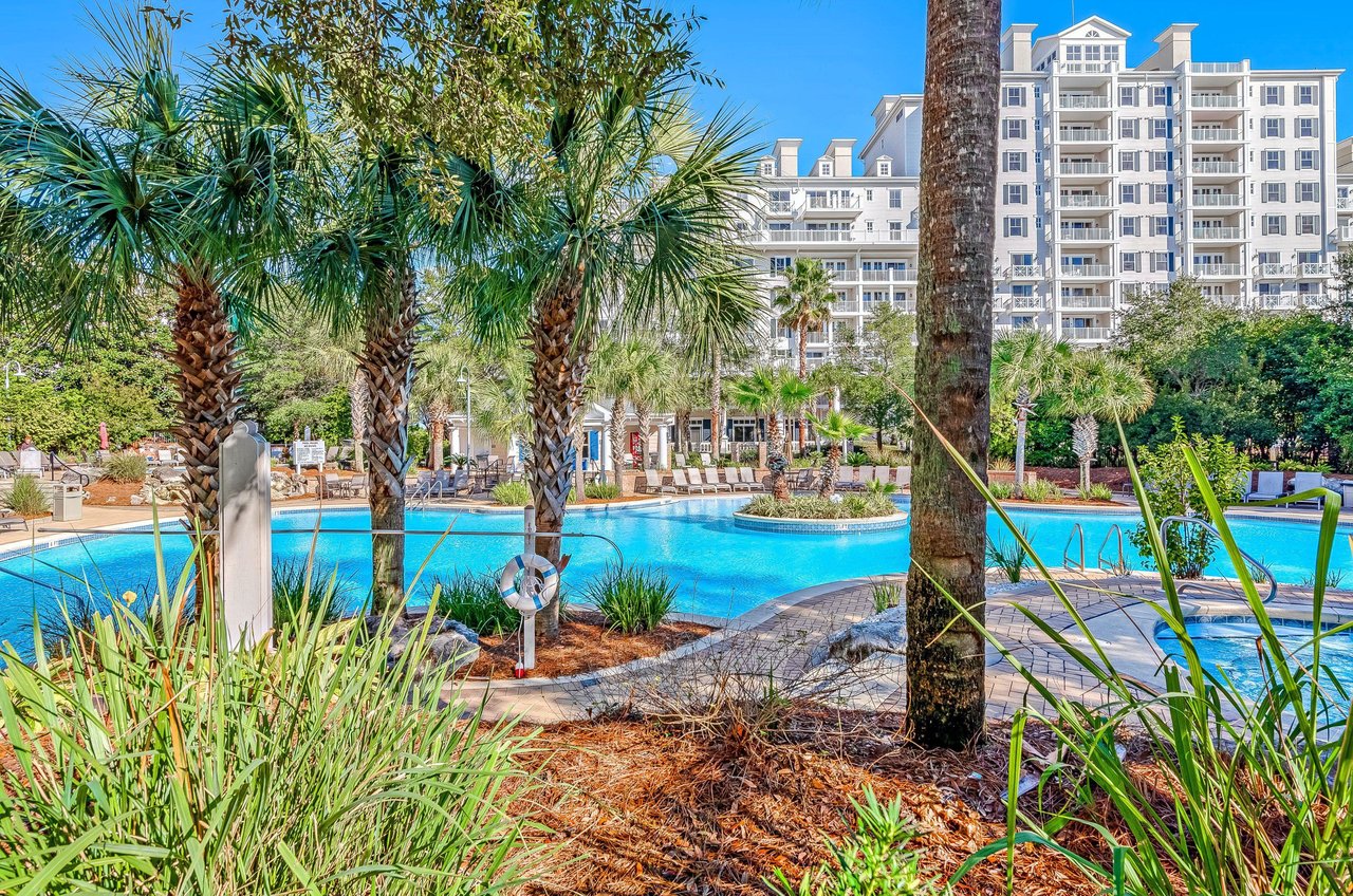 The pool are features tropical landscaping, including several towering palm trees.
