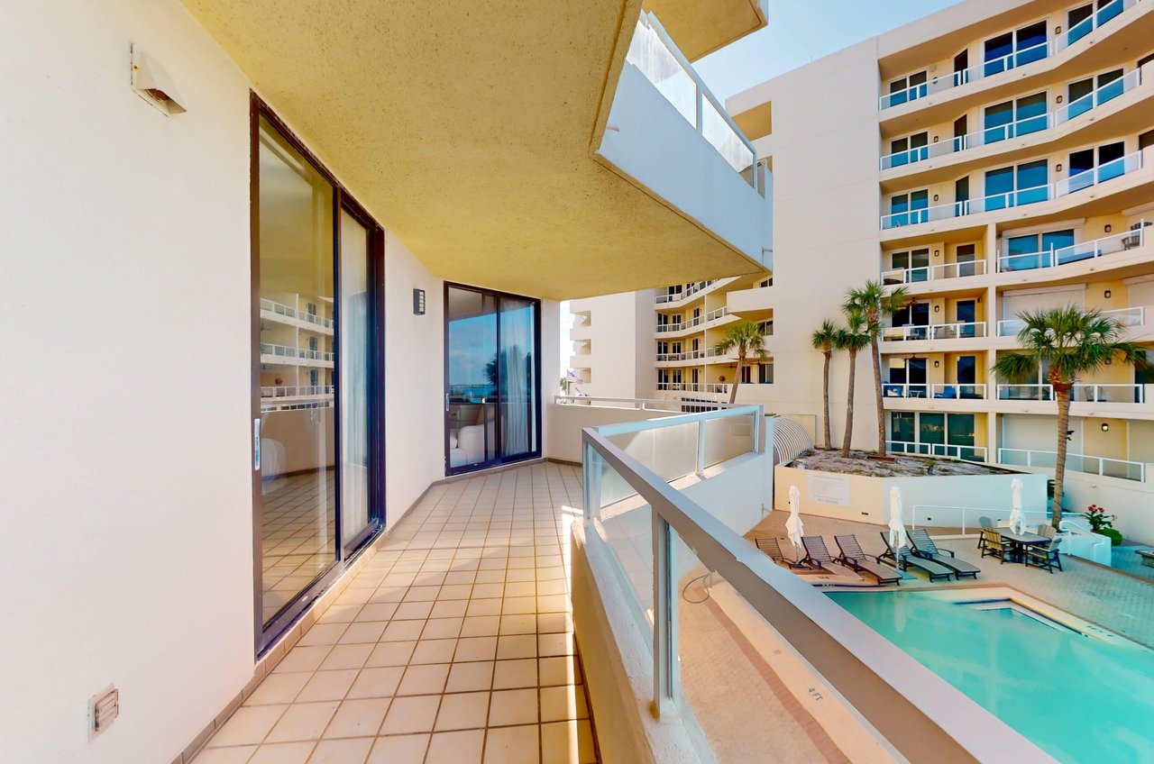 A condos tile balcony overlooks the community swimming pool.