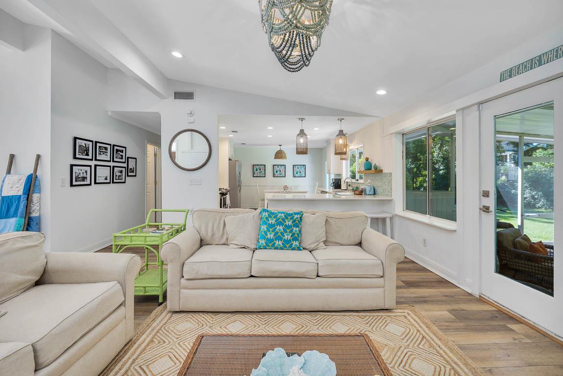 Alternate view of the main house living room at 530 Delegal showing seating facing the kitchen area behind the couch and glass doors opening to the screened porch.