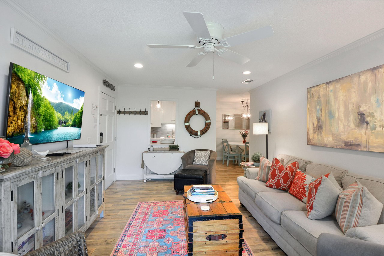 Living room with sofa seating, smart TV, and open flow to the dining area and kitchen.