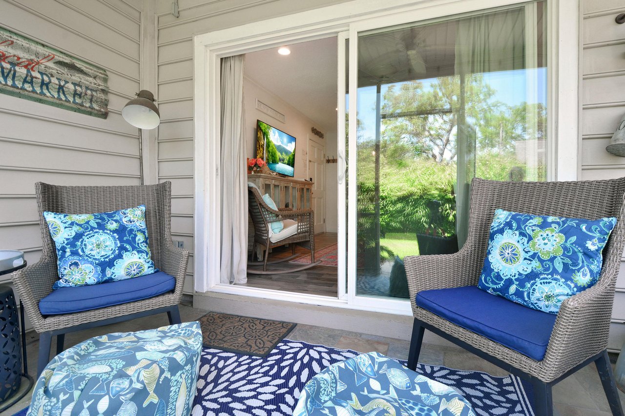 Screened patio just off the living room with two chairs and a view of the landscaped grounds.