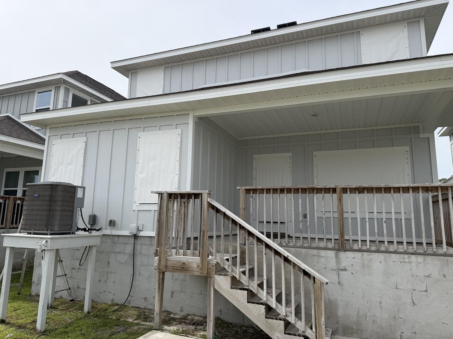 White storm coverings over rear windows and doors of a vacation home before the PKRM office closure.