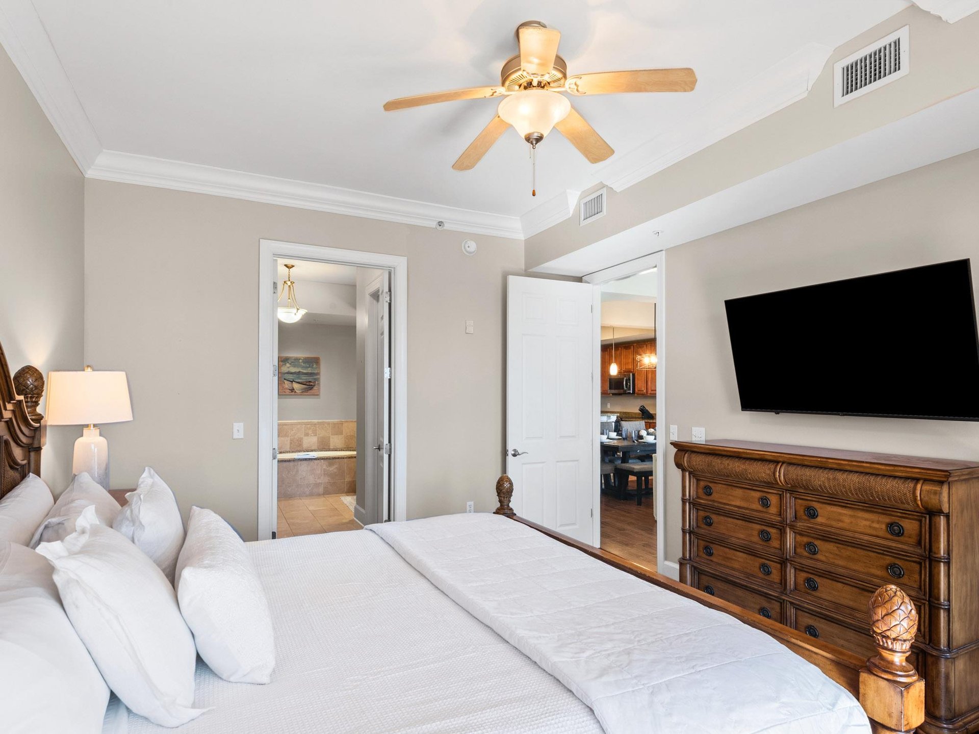 Primary bedroom with plush linens, ceiling fan, and direct bathroom access for ultimate comfort.