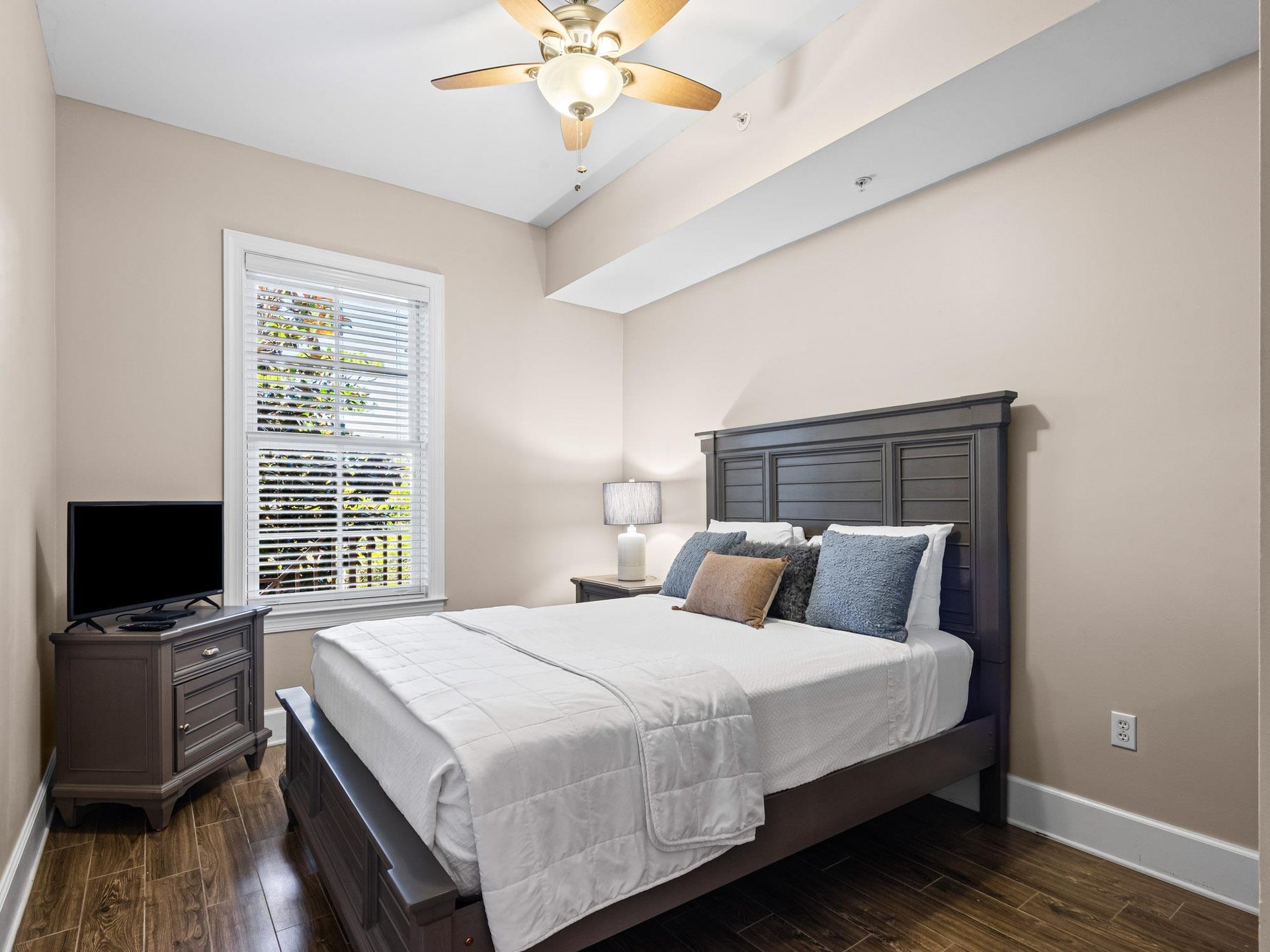 Unwind in your serene bedroom with gentle ceiling fan breeze, and natural light through shuttered windows.