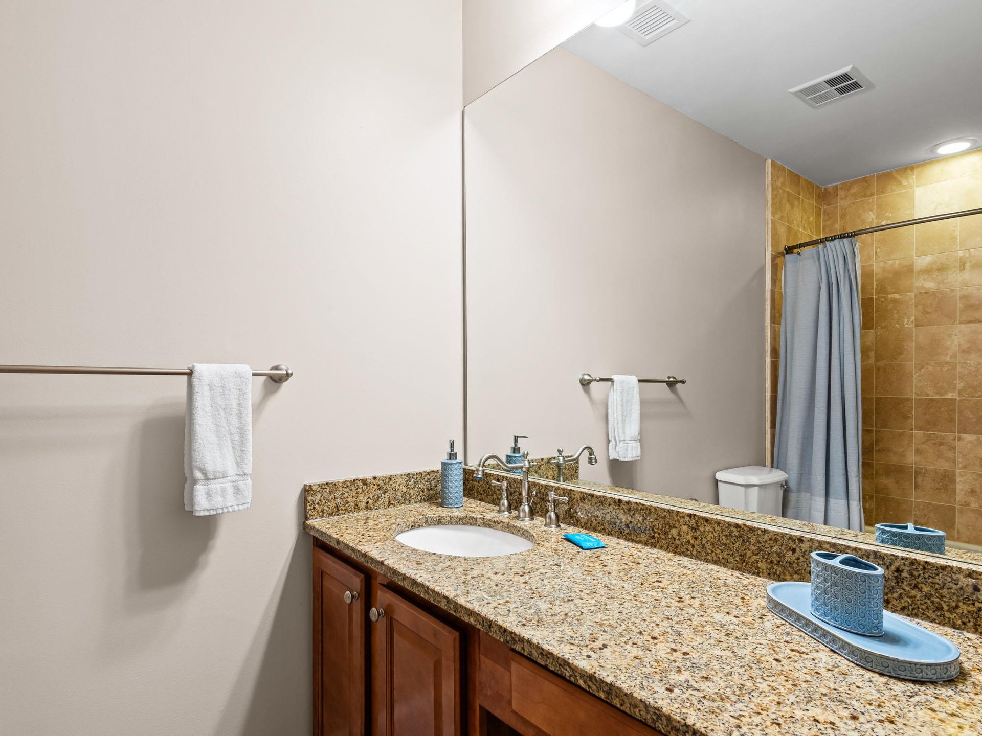 Spacious bathroom features granite countertops, warm wood cabinetry, and thoughtful amenities to start each morning refreshed and relaxed.