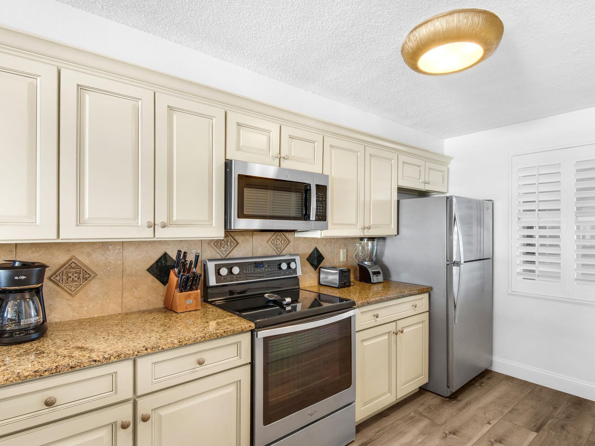 Fully equipped kitchen features cream cabinetry, granite countertops, and stainless steel appliances for all your cooking needs.