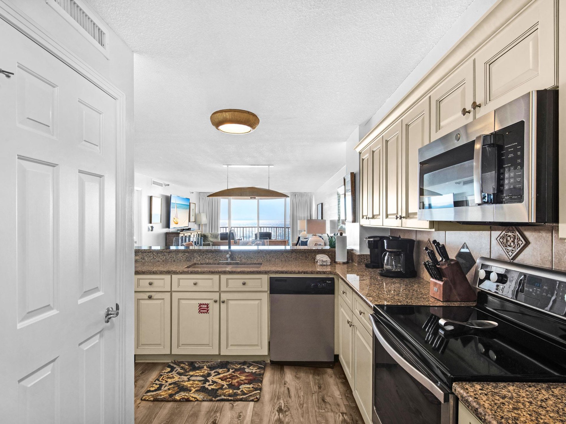 Fully equipped kitchen features granite counters and opens to breathtaking ocean views—perfect for morning coffee while waves sparkle beyond.