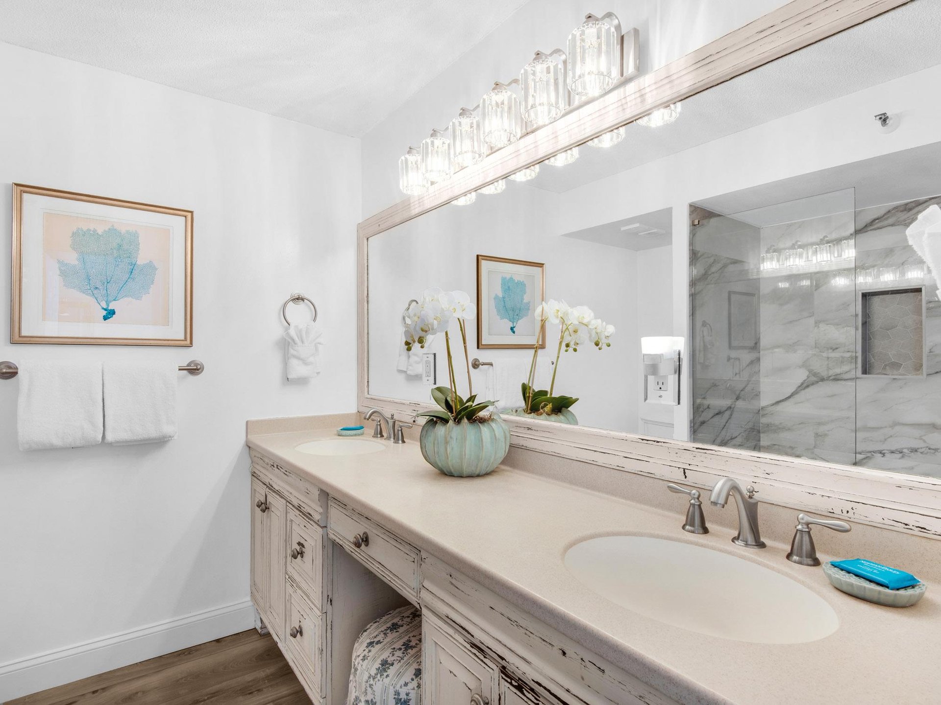 Bathroom 1 features dual sinks with coastal décor and a luxurious marble shower for relaxing mornings.