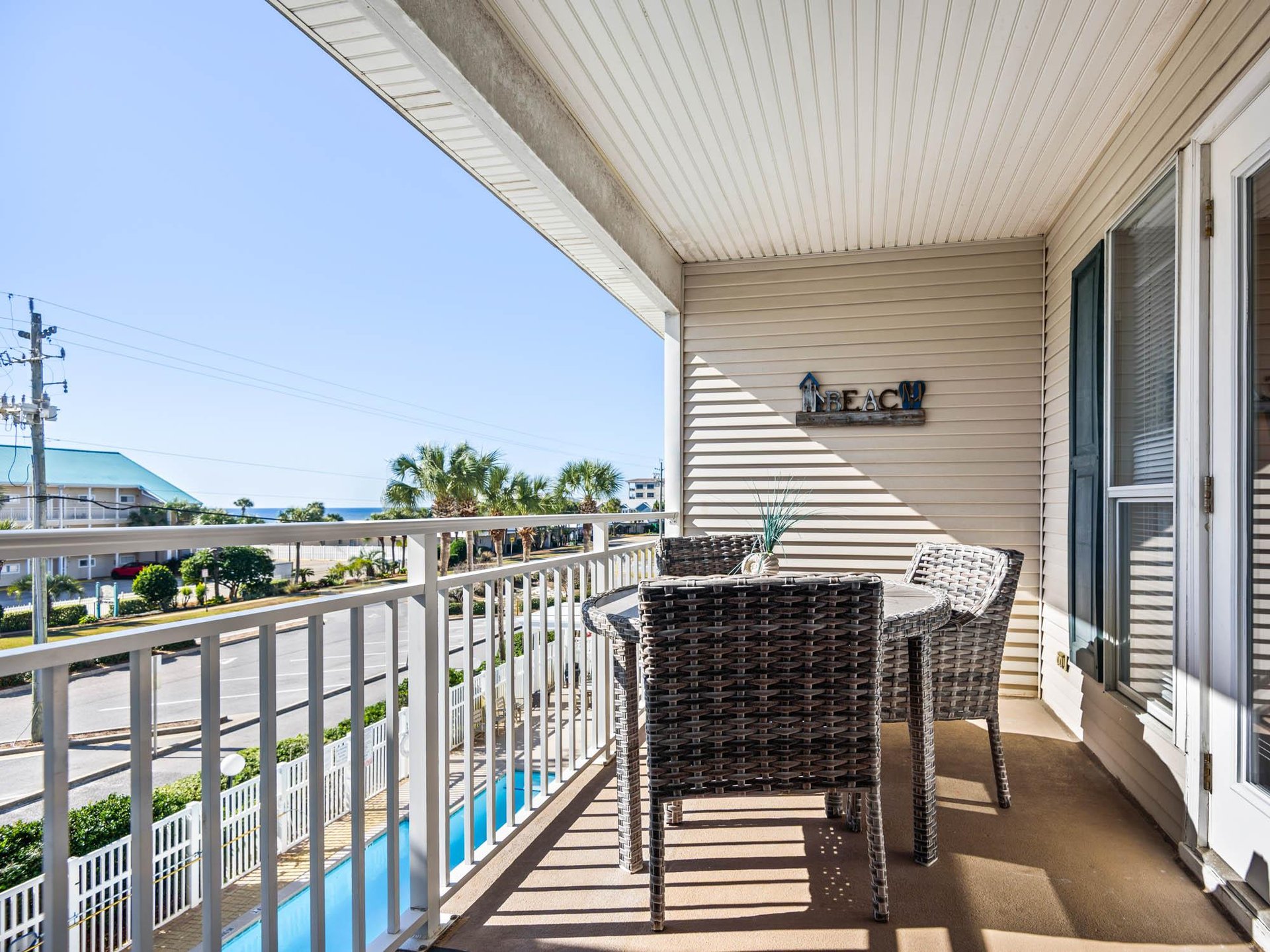 The private balcony offers wicker seating and stunning ocean views, perfect for morning coffee or sunset drinks with the beach just steps away.