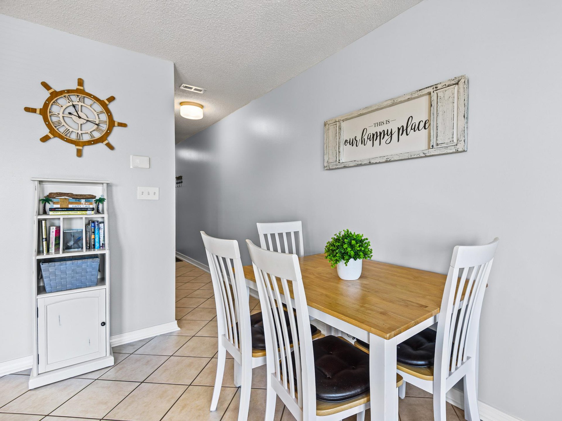 The dining space welcomes with warm wood tones and charming coastal décor