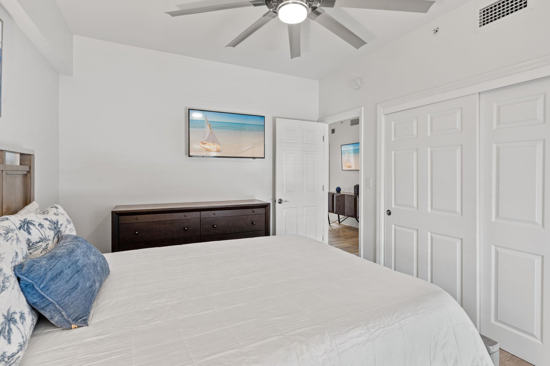 Drift off in your bright 2nd floor queen bedroom with coastal charm—soft linens, ocean artwork, and a ceiling fan for perfect comfort.