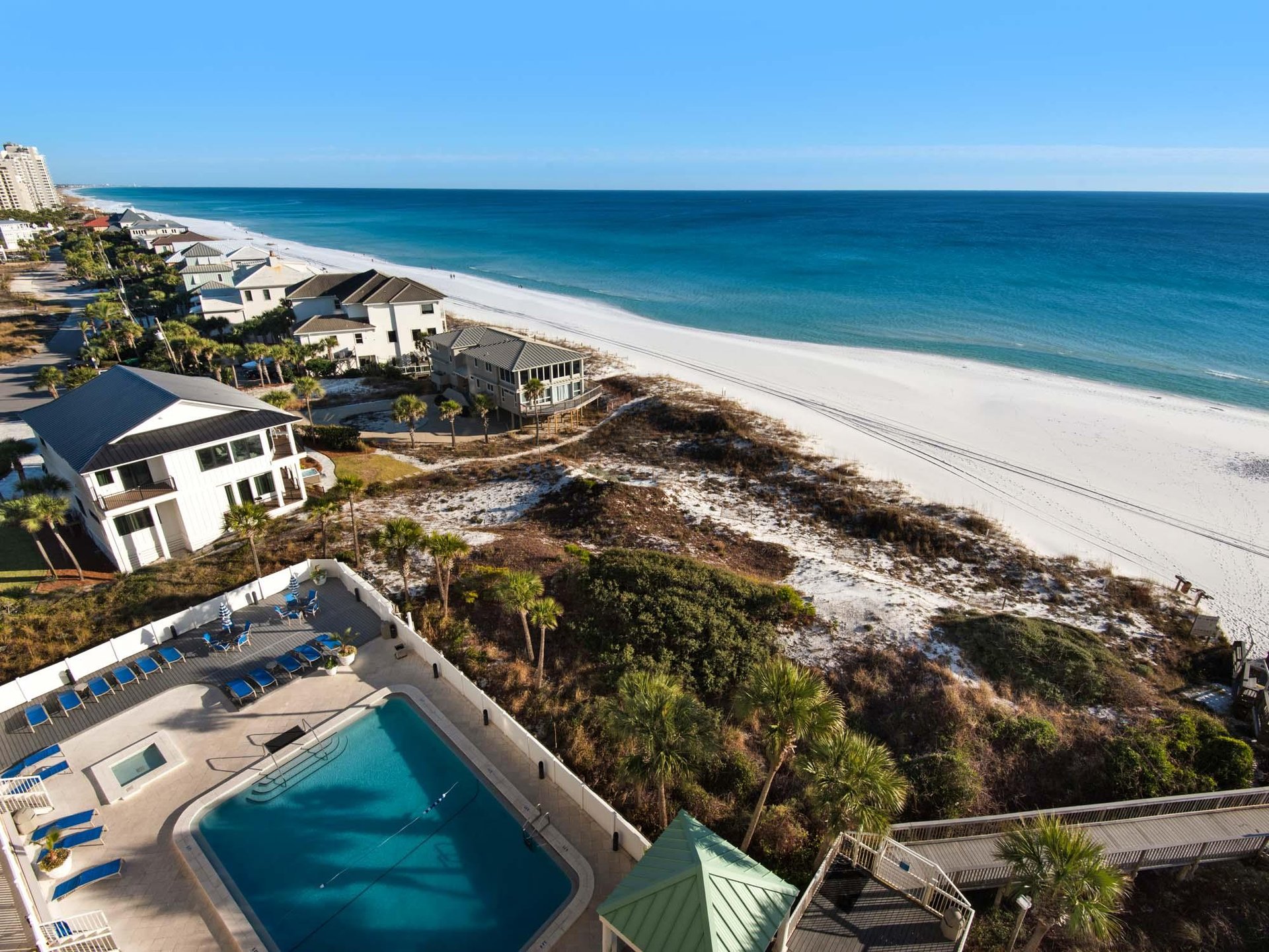 Stunning beachfront property aerial view showcasing pristine white sand beach, turquoise waters, and luxury vacation homes along the coastline.