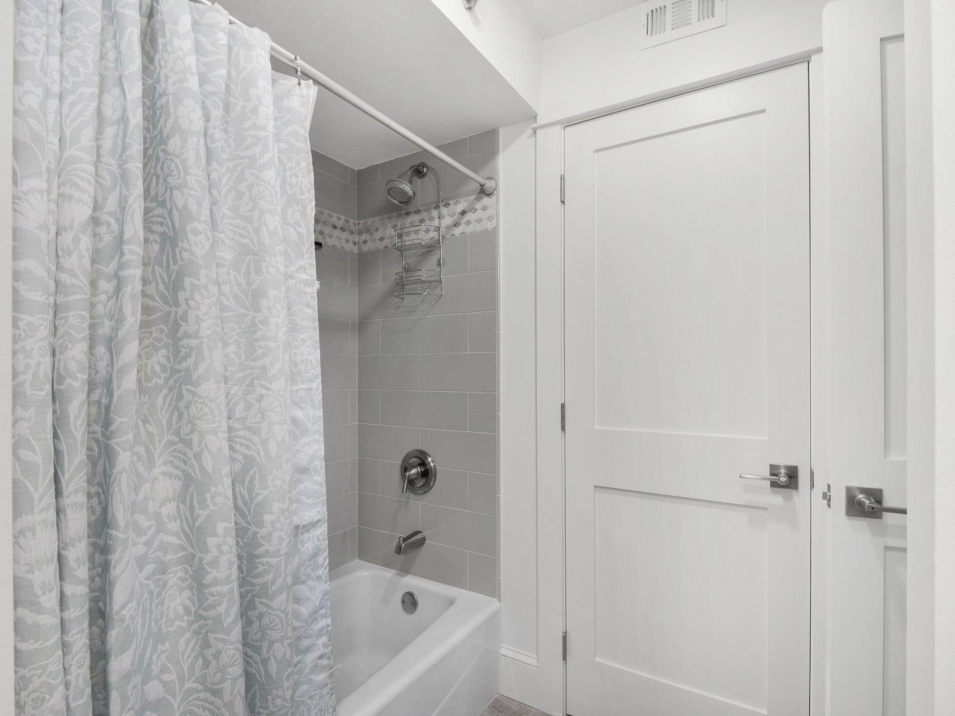 Unwind in your pristine bathroom featuring a relaxing tubshower combo with elegant gray tile and fresh linens.