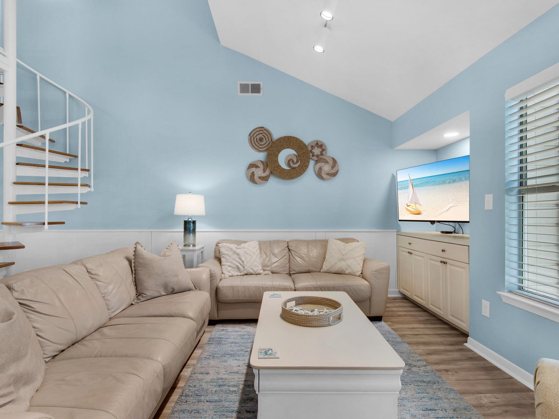 Sink into plush sofas in your bright coastal living room, where soothing blue walls and beach artwork create the perfect retreat.