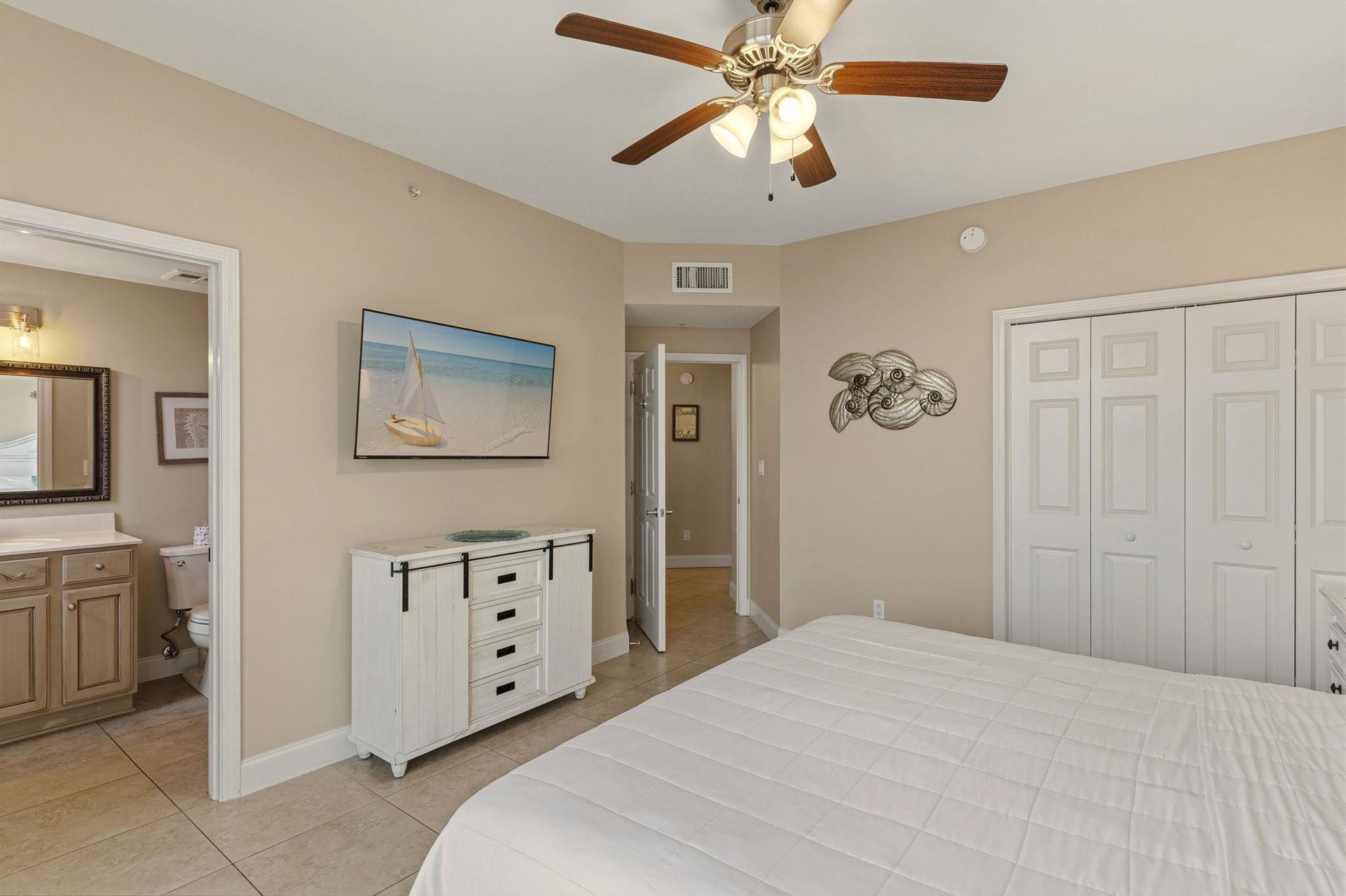 Bedroom 2 features a comfortable bed, coastalthemed artwork, and ceiling fan to keep you cool.