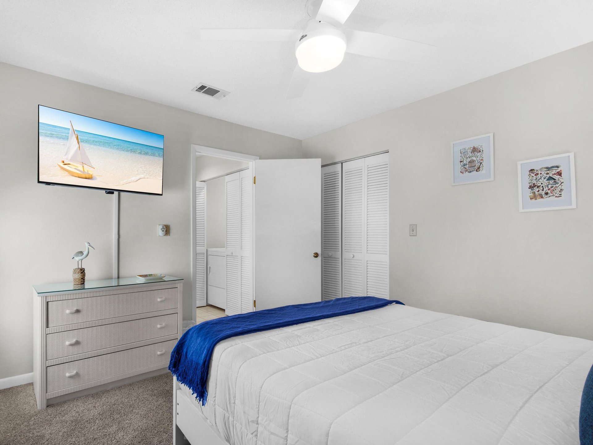 Drift off to sleep in your peaceful bedroom with a wallmounted TV and coastal artwork setting a serene mood.