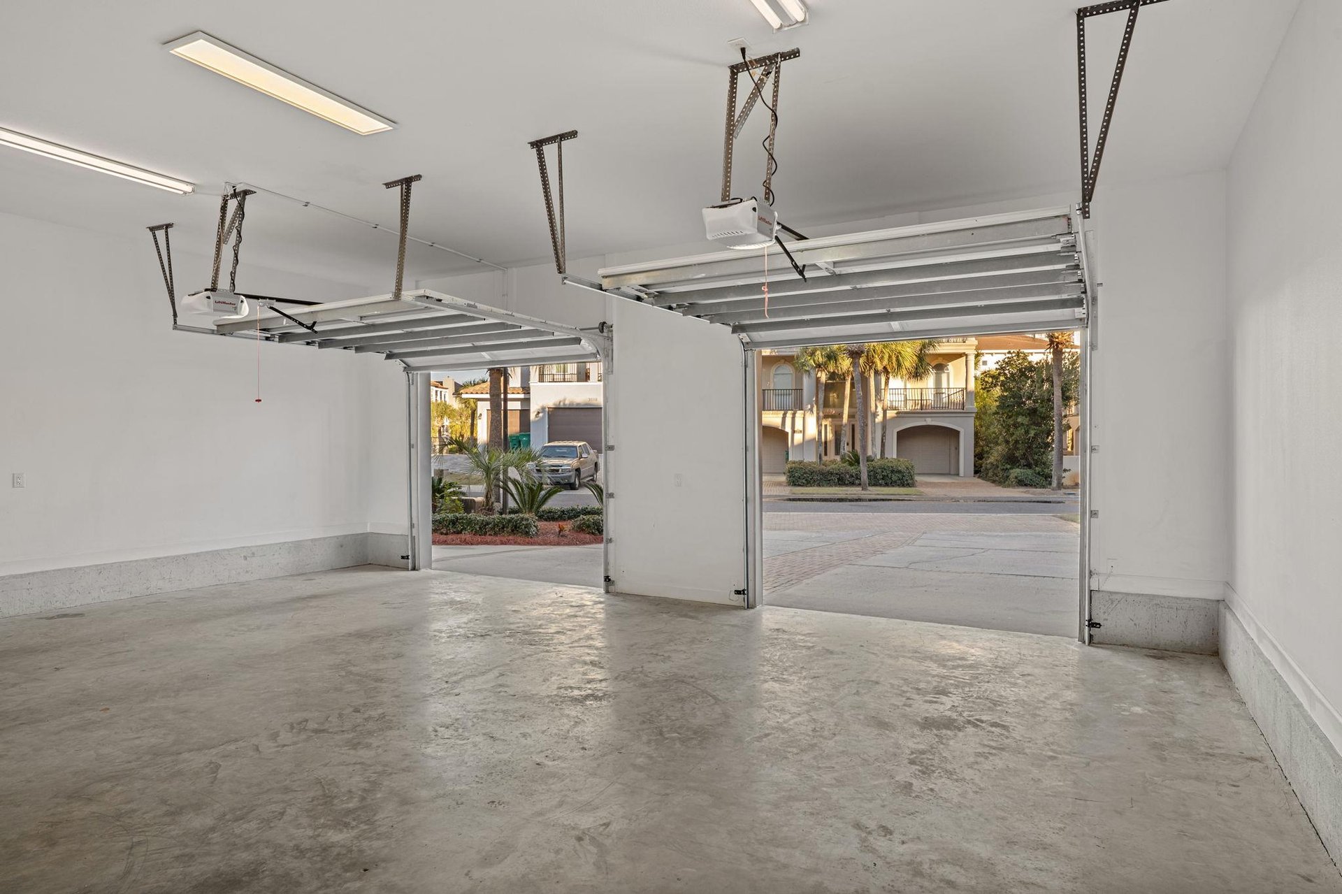 Spacious twocar garage with automatic doors opens to a quiet residential street lined with elegant homes and mature landscaping.