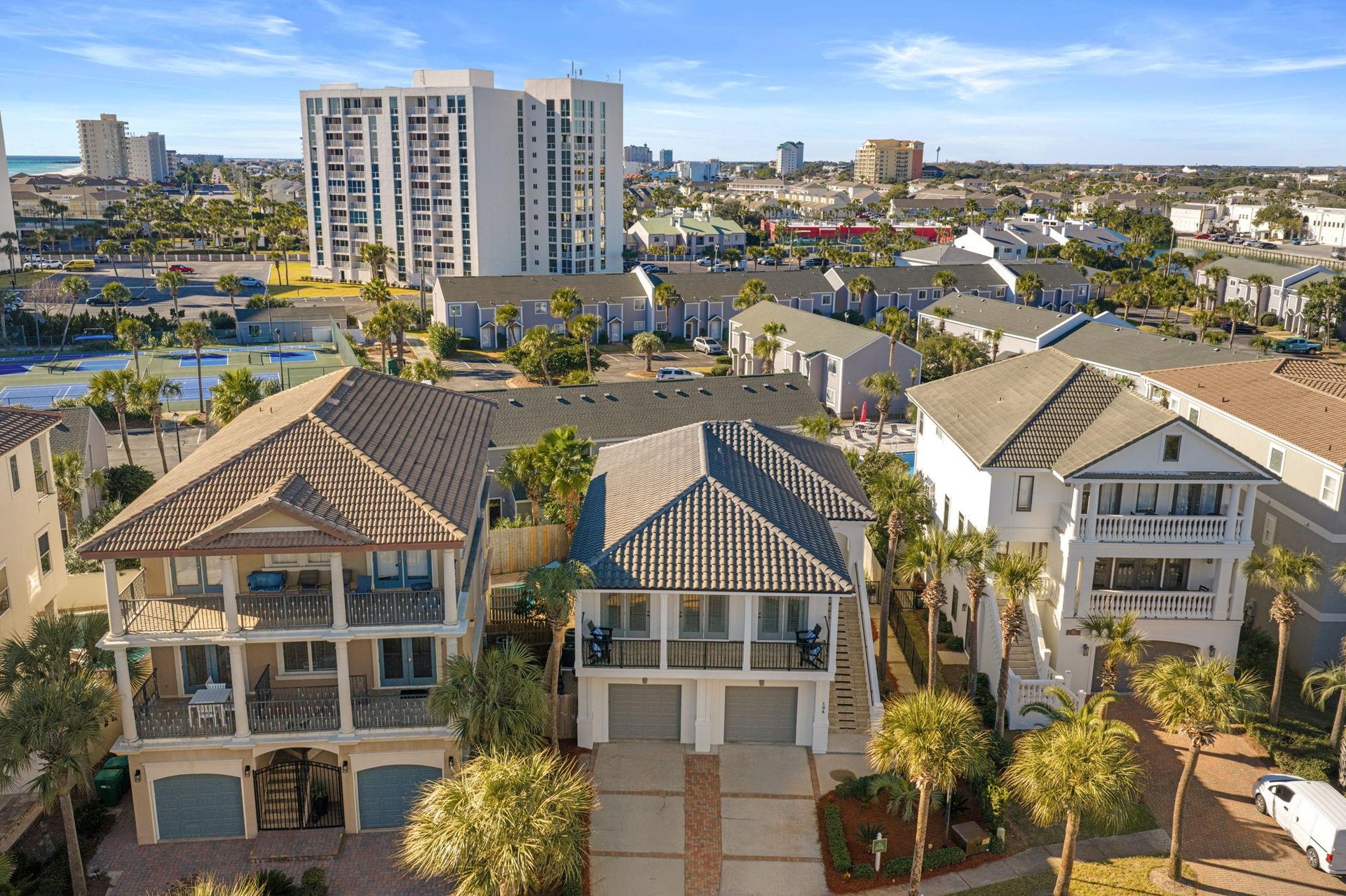 Aerial view of coastal residential properties with palm trees and city skyline in a vibrant beachside community.
