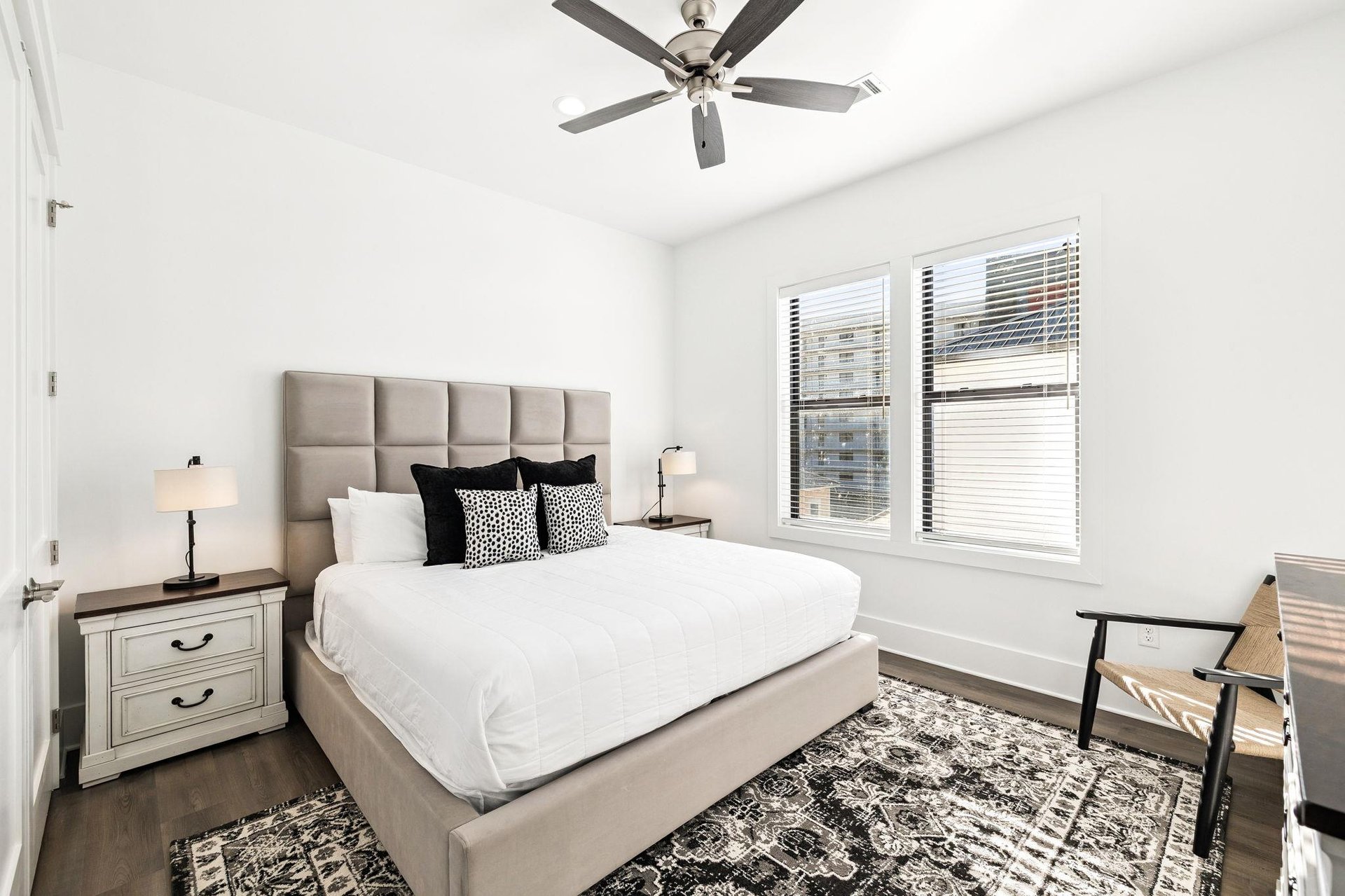 Sink into crisp white linens and plush pillows in your peaceful bedroom retreat, where gentle breezes from the ceiling fan create perfect comfort.