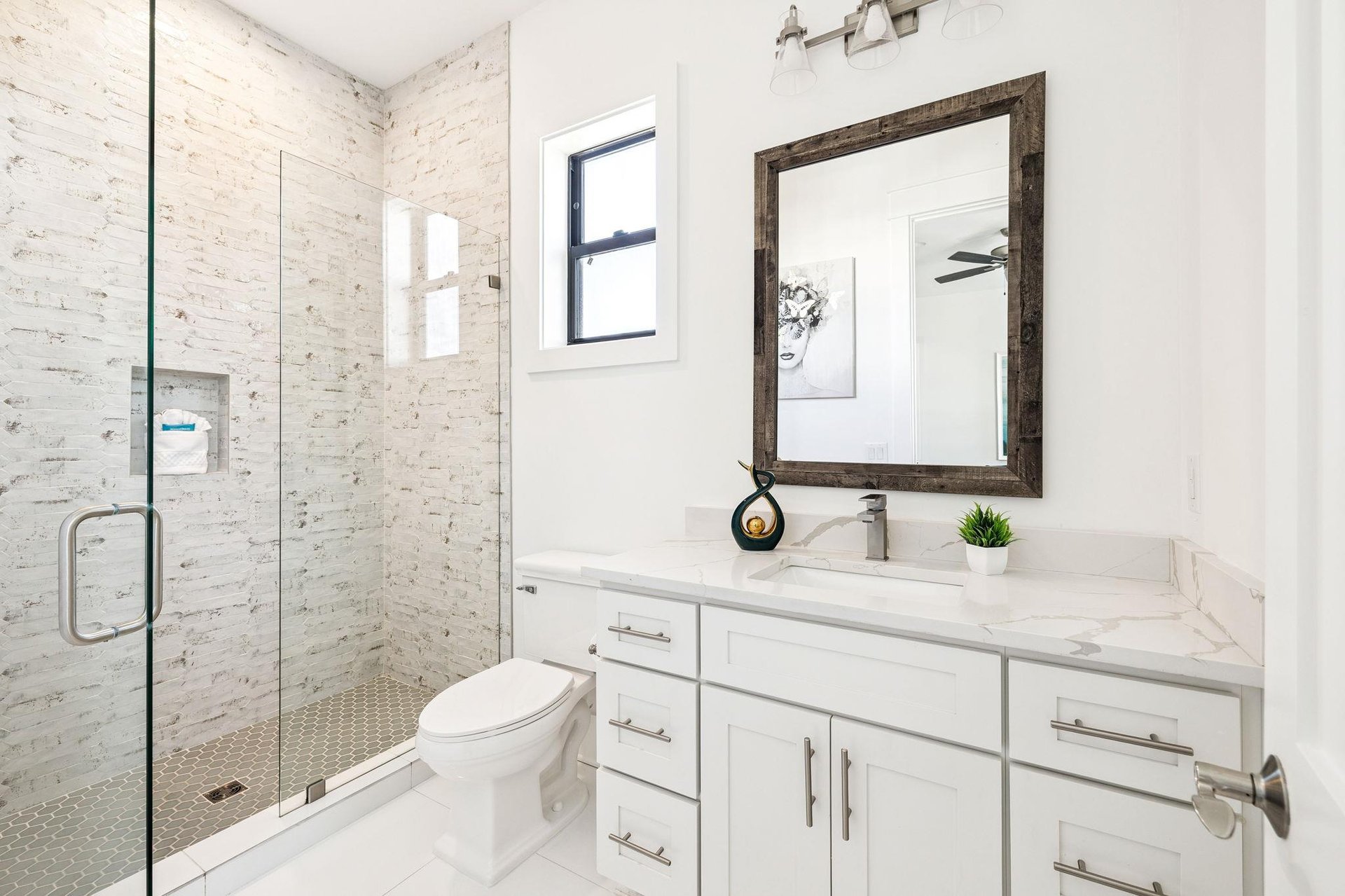 Step into your pristine bathroom where white marble meets exposed brick. The spacious shower and elegant vanity create a perfect morning retreat.