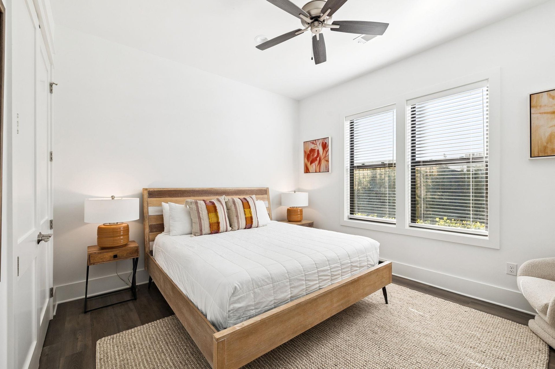 Drift into peaceful sleep in your bright bedroom with crisp linens, warm wood tones, and a gentle ceiling fan overhead.