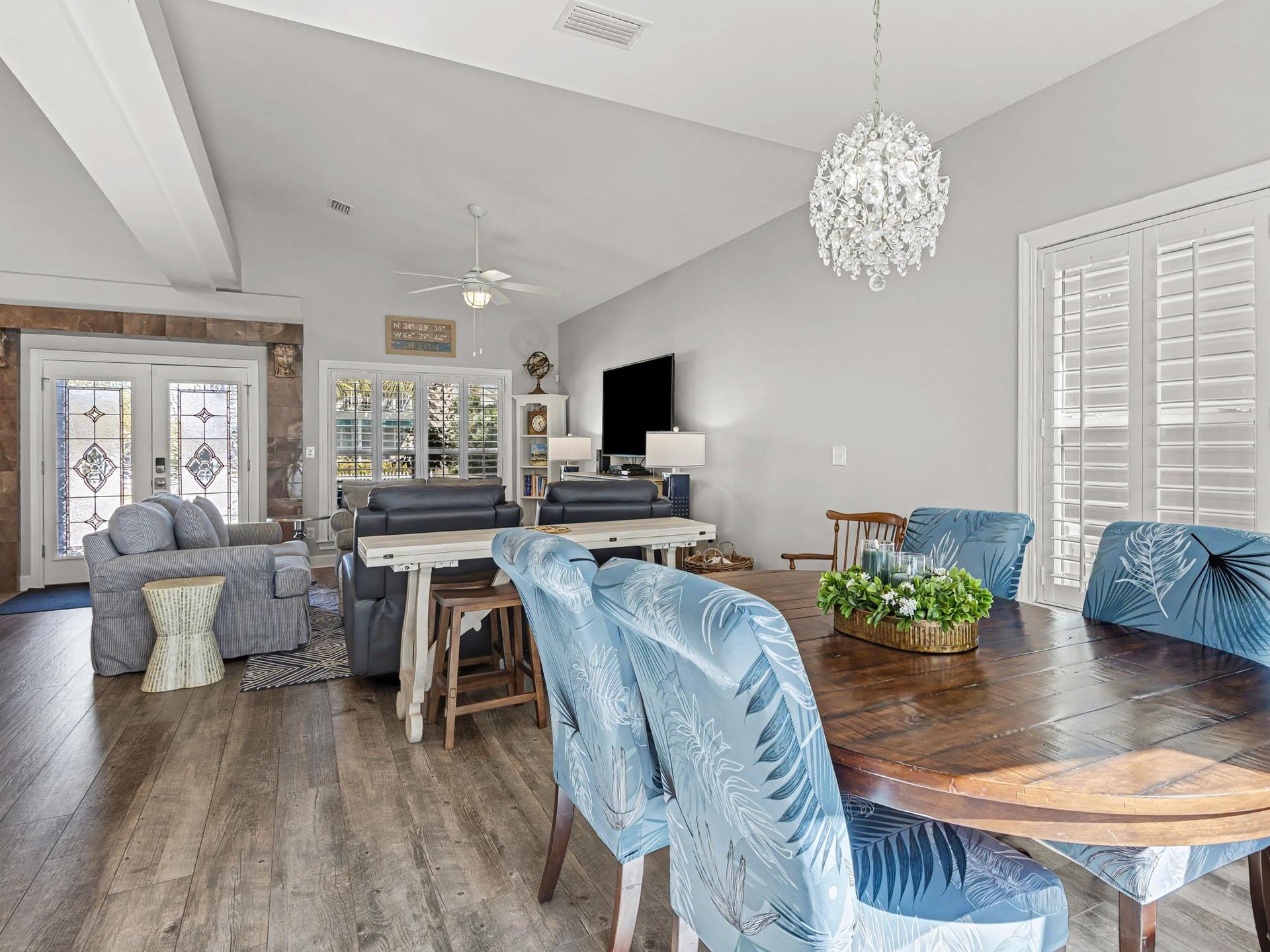Settle into your elegant open living space where coastal blues meet modern comfort, complete with sparkling chandelier and rich wood floors.