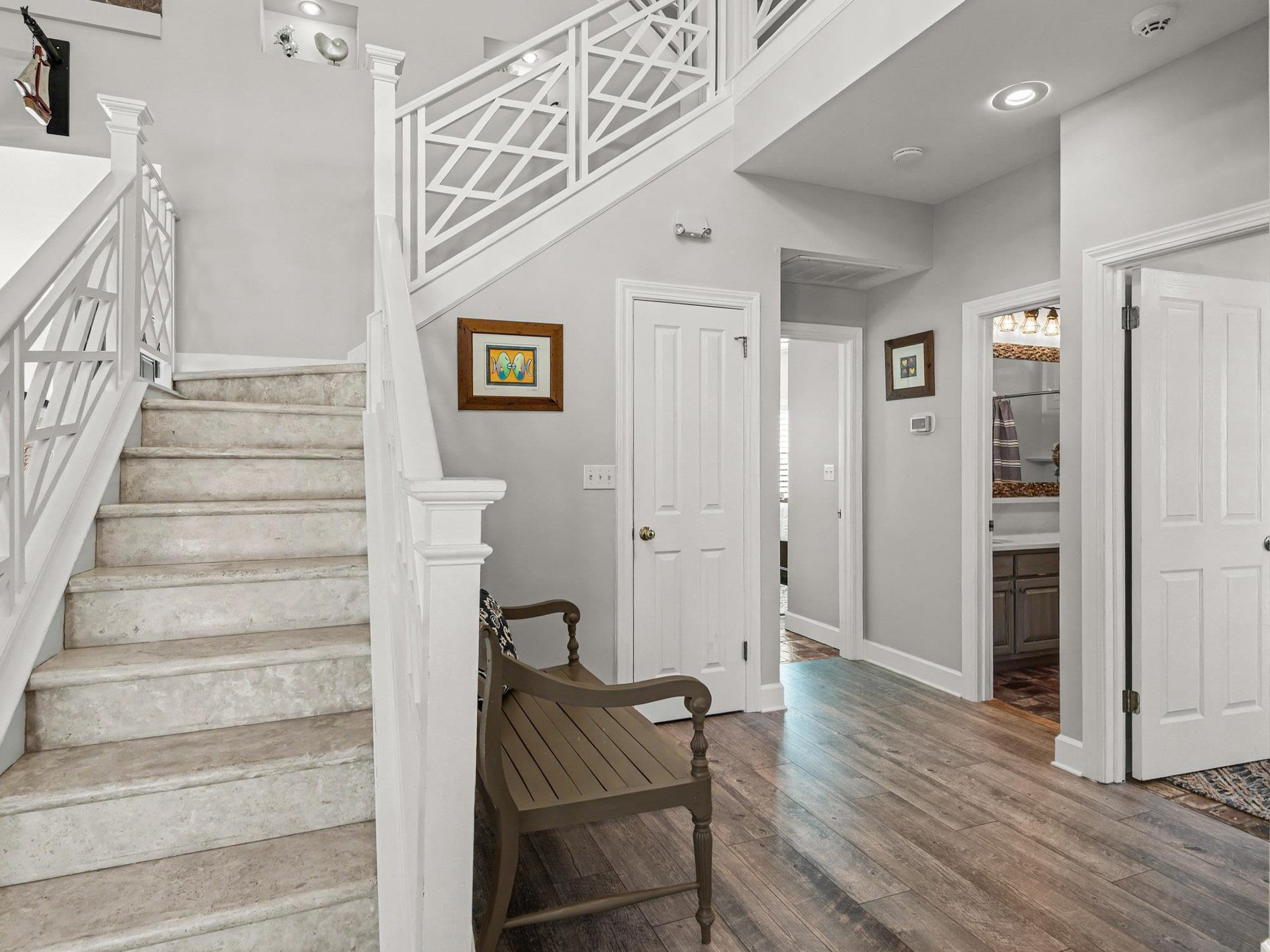 Step into your elegant entryway featuring rich hardwood floors, sophisticated gray walls, and a welcoming wooden bench where you can pause and settle in.