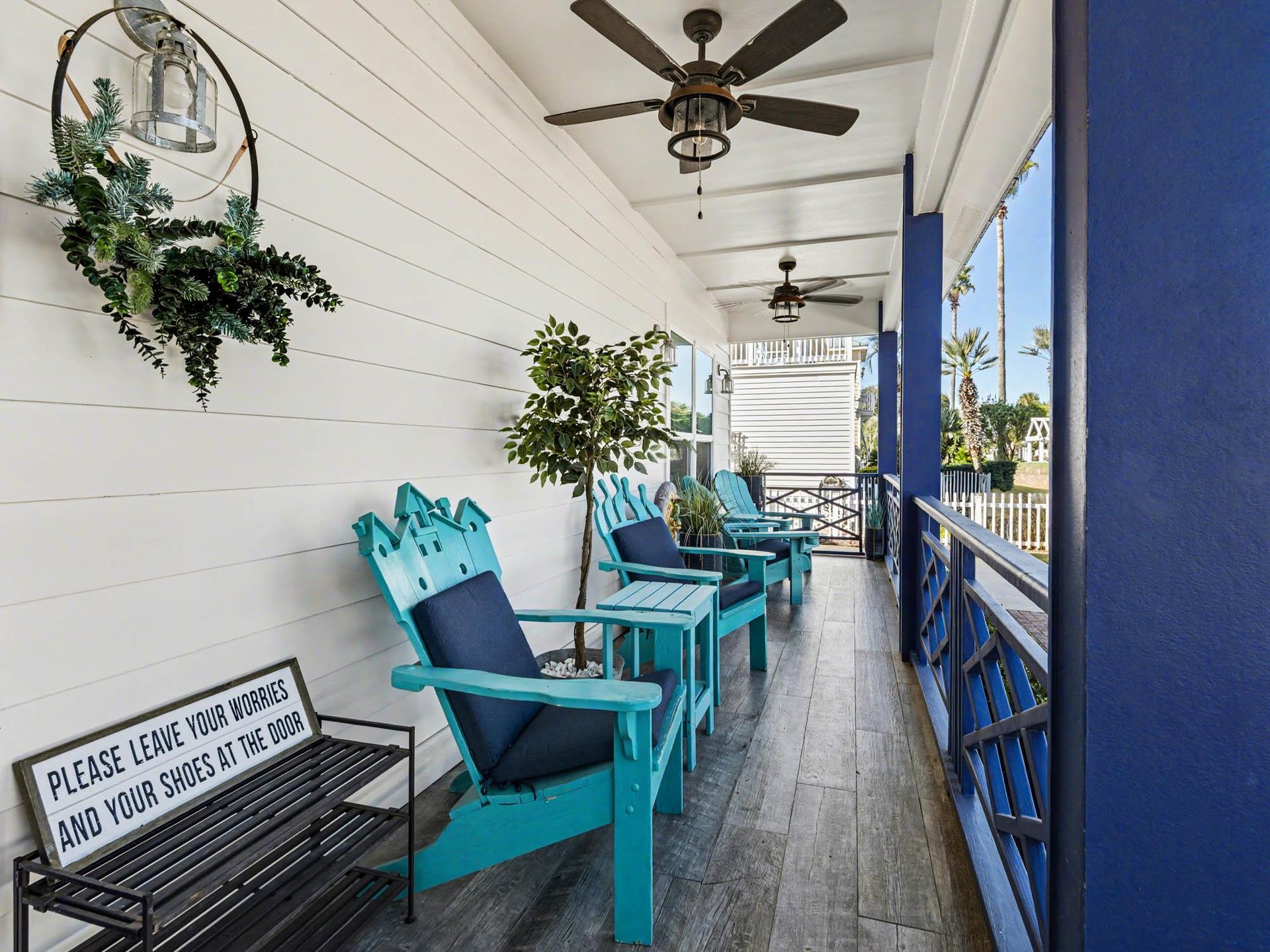 Unwind on your covered porch with turquoise chairs and coastal breezes, where ceiling fans keep you cool while palm trees sway nearby.