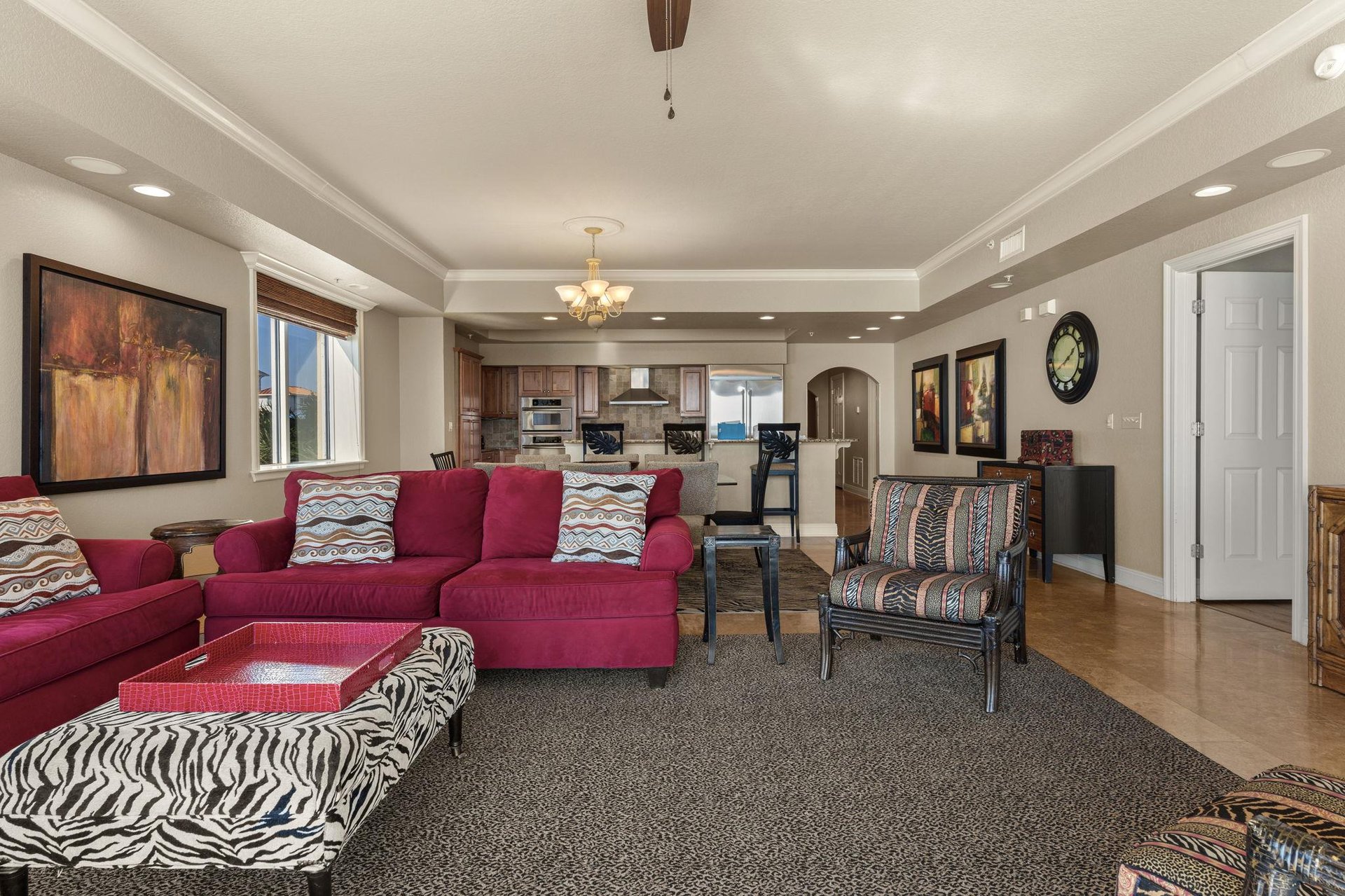 Settle into your stylish openconcept living space with plush burgundy sectional and vibrant patterns, flowing seamlessly into the gourmet kitchen.