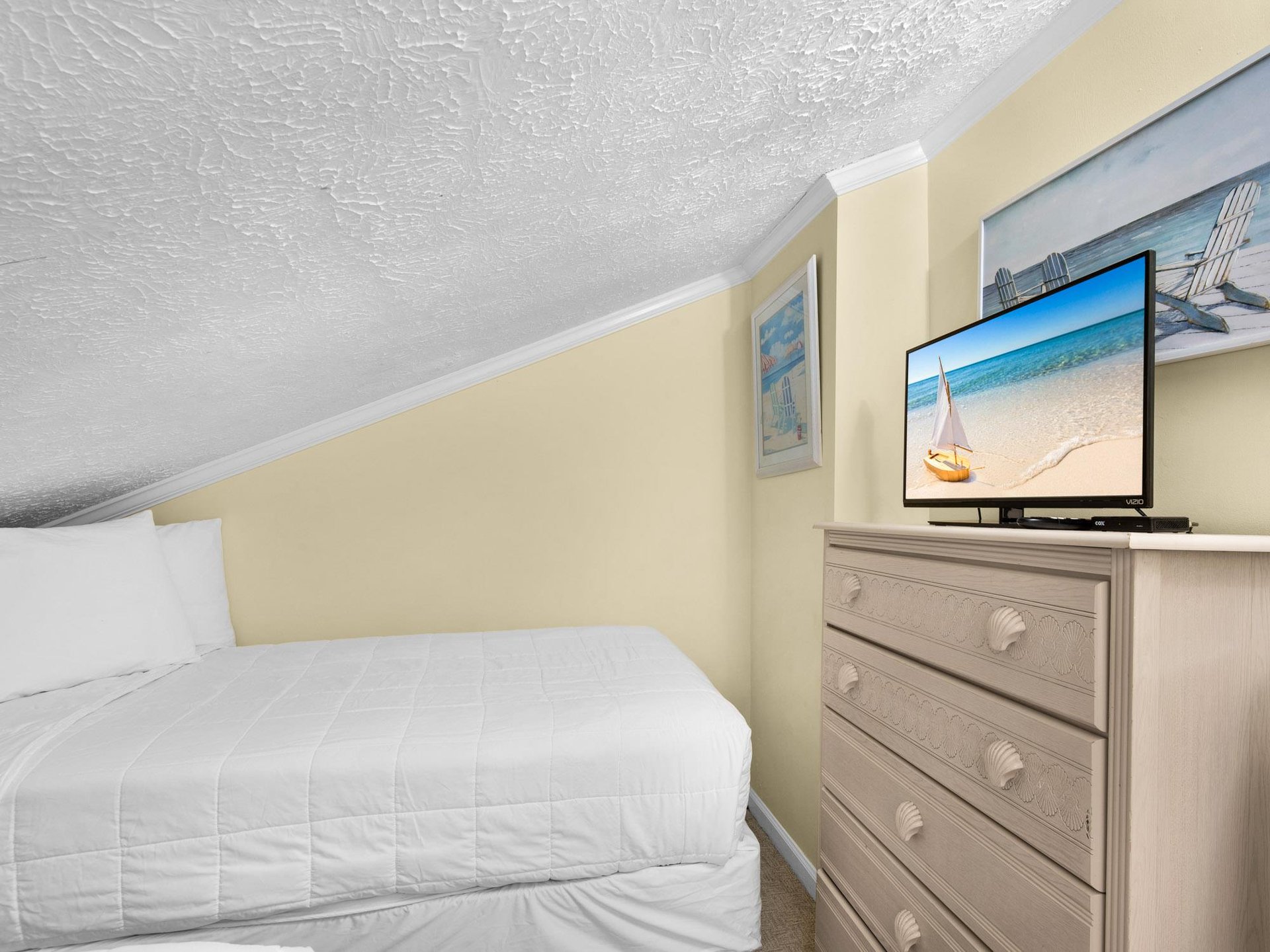 Cozy up in the peaceful guest bedroom with soft linens, coastal decor, and flatscreen TV for relaxing evenings.