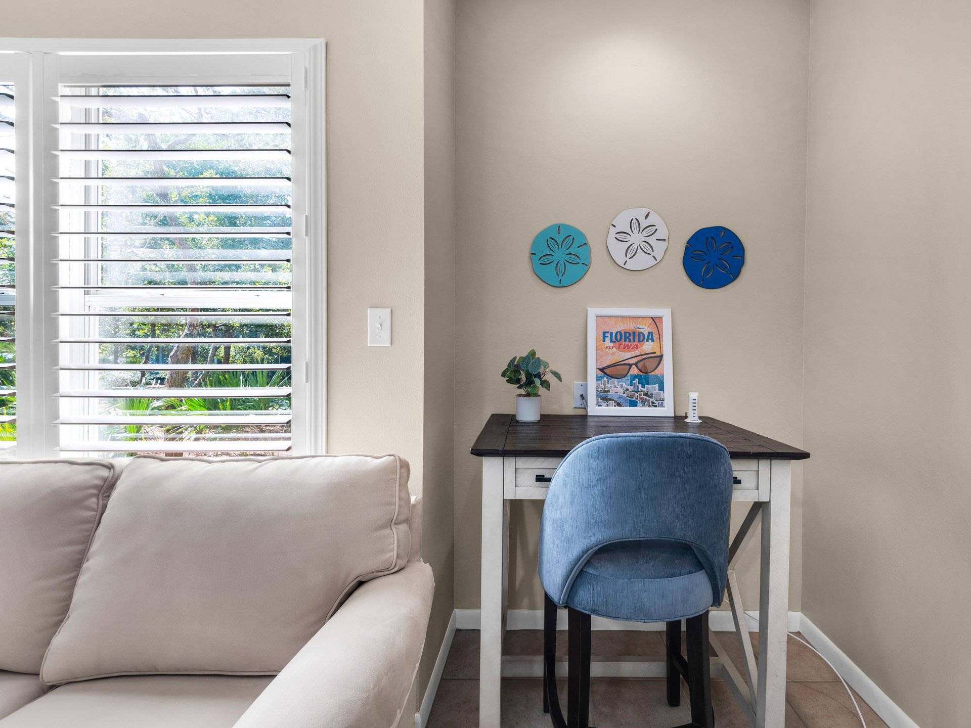 Your dedicated workspace awaits with a comfortable blue chair and natural light streaming through plantation shutters.