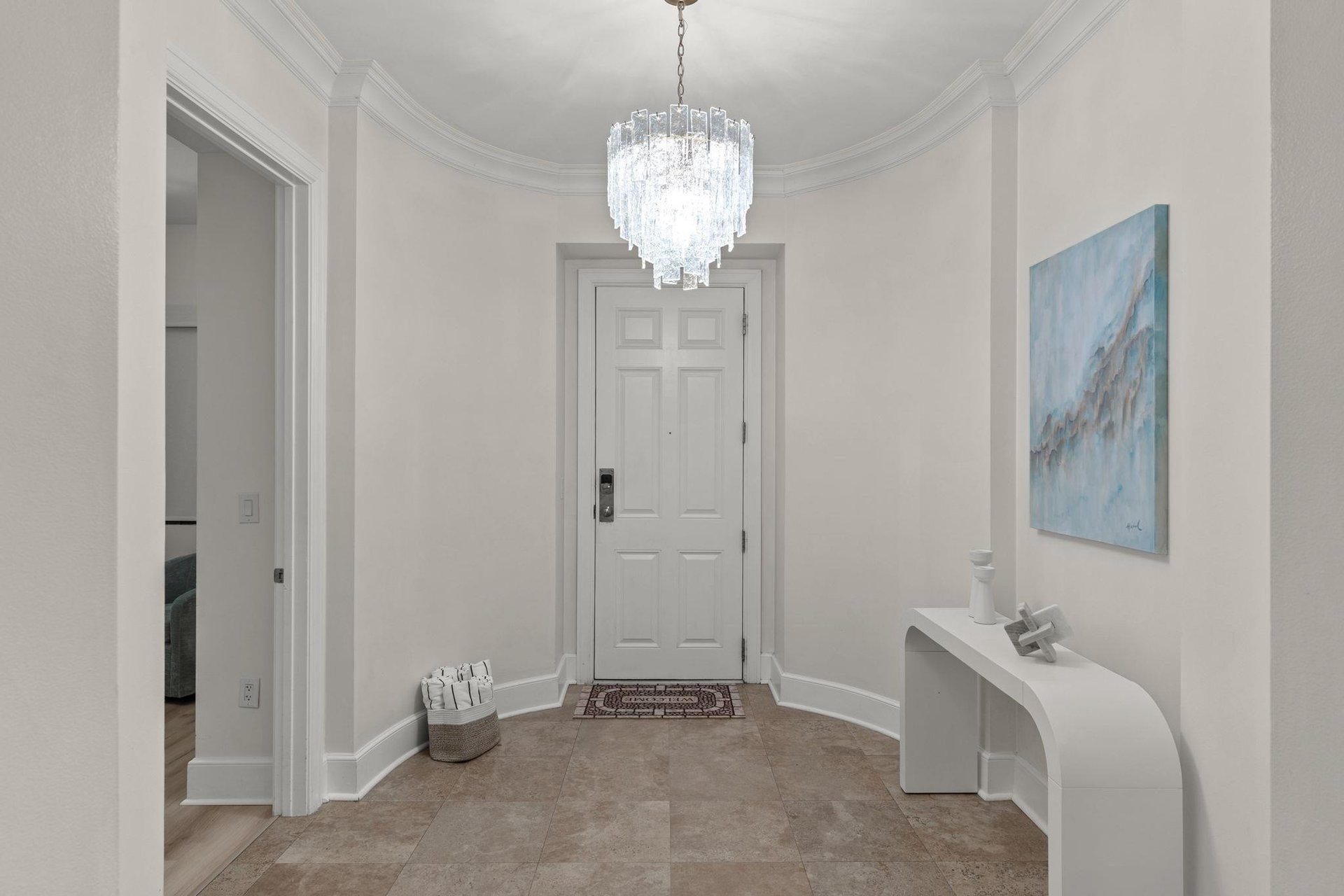 Step into your elegant foyer where crystal chandelier light dances across pristine walls, creating an instantly welcoming atmosphere for your stay.
