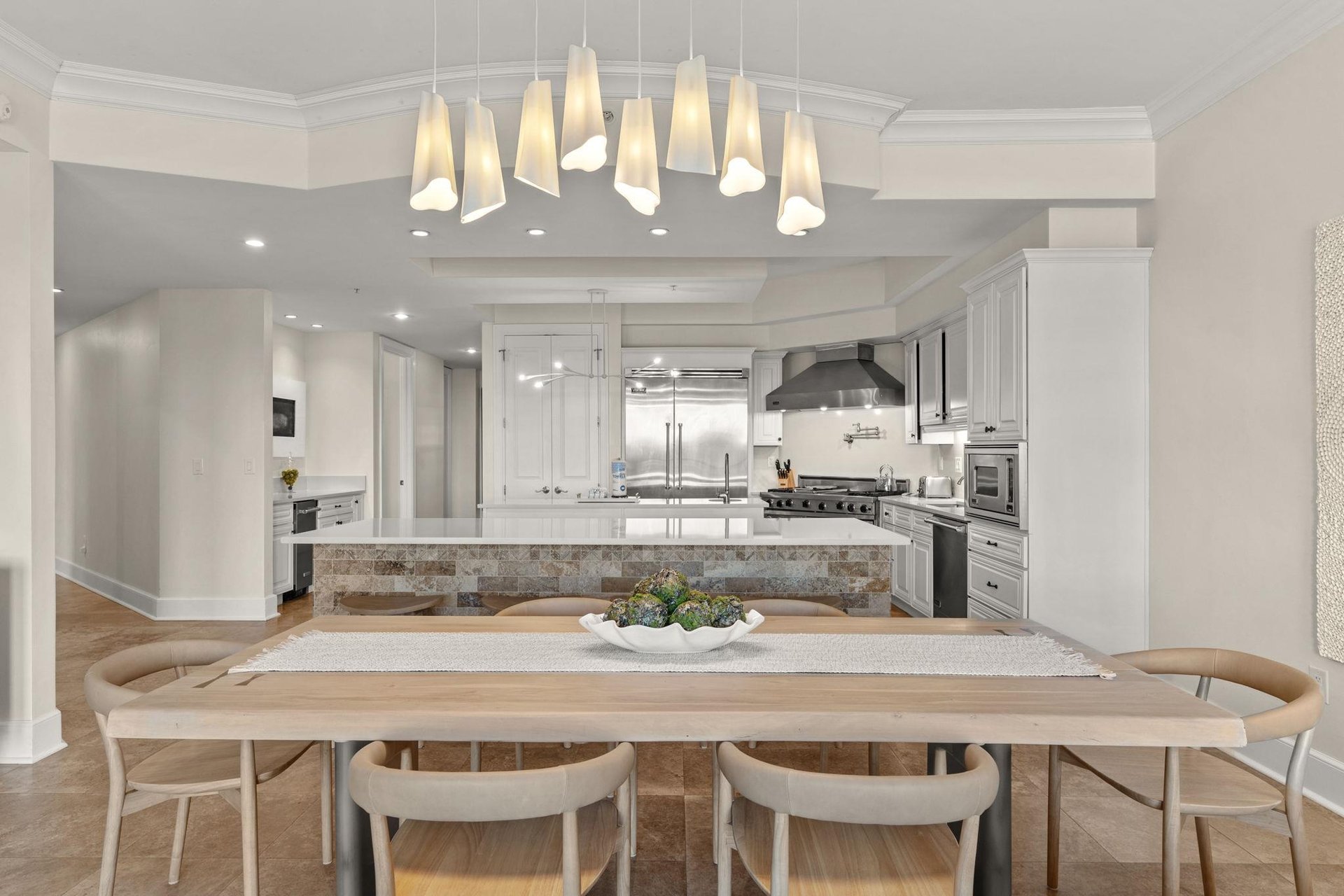Your openconcept kitchen and dining space features elegant pendant lighting, modern appliances, and a warm wood table perfect for memorable meals.