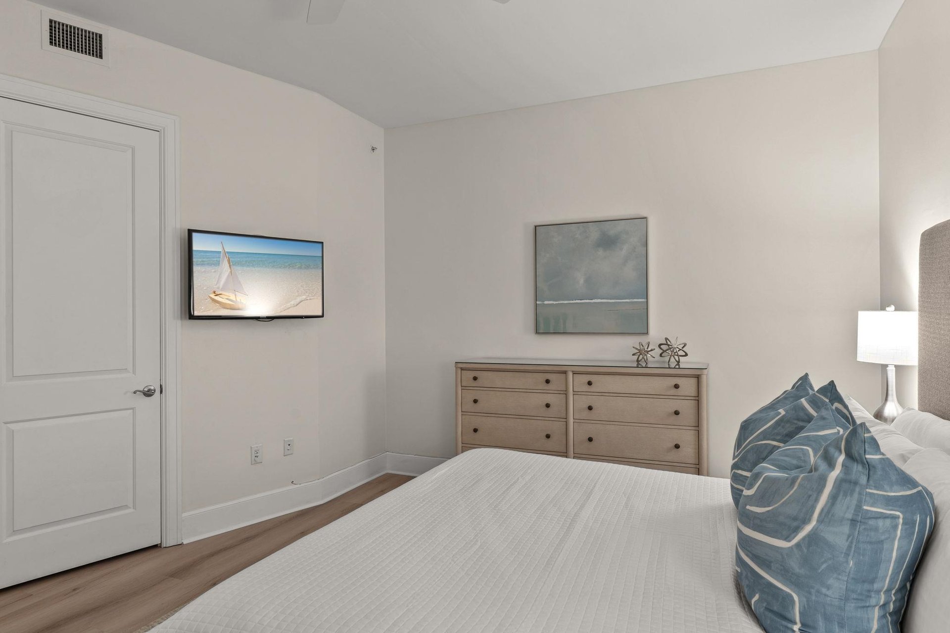 Drift off in your serene bedroom featuring coastal artwork and soft bedding that invites peaceful sleep.