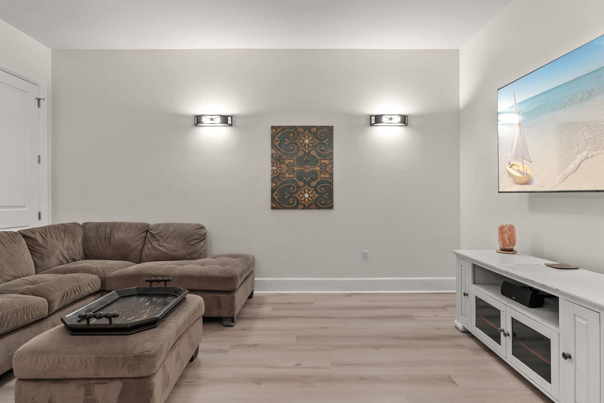 Sink into plush seating and unwind in your private tv room, complete with modern entertainment setup and coastal artwork.