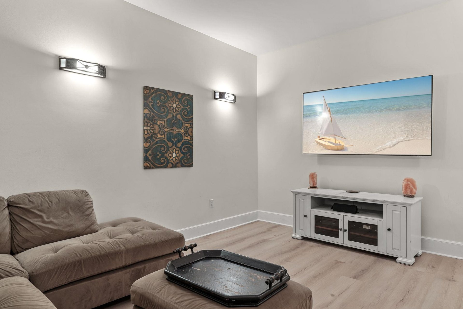 Sink into plush seating and enjoy your favorite movies or shows on the large TV, with coastal artwork creating a serene atmosphere.