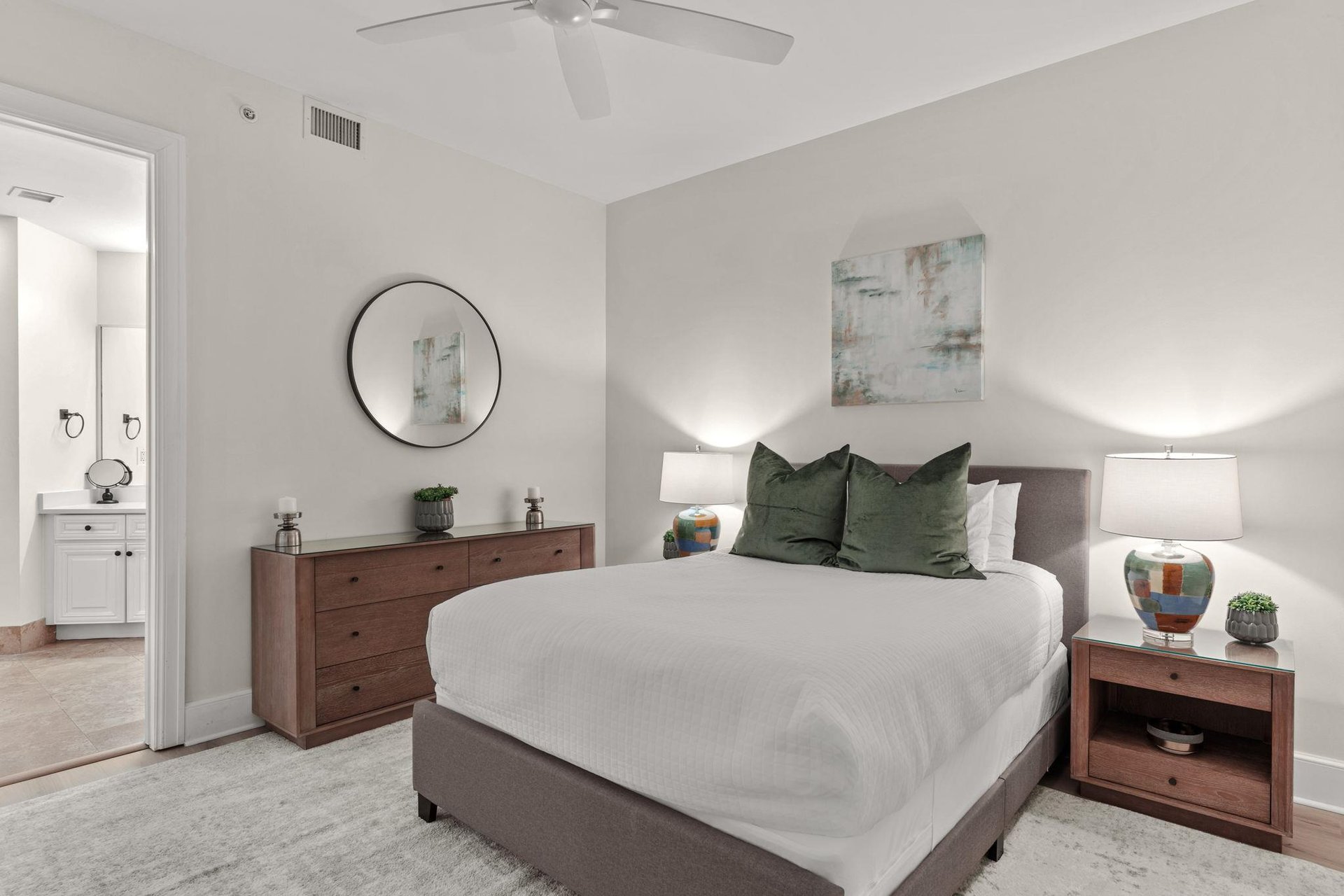 Your peaceful bedroom retreat features a plush bed with forest green pillows and warm wood furnishings for restful nights.