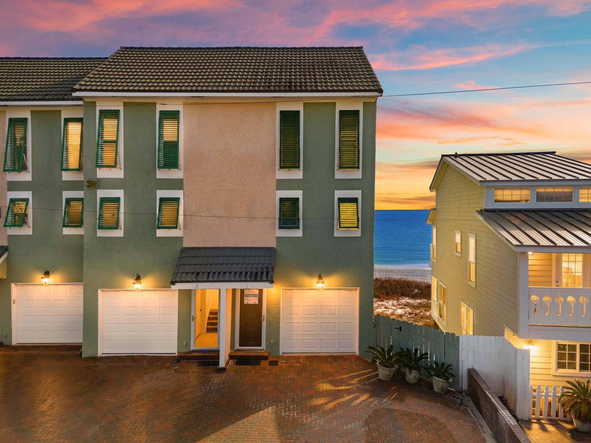 Multilevel beach property with private garages and stunning Gulf views at sunset, perfectly positioned near the sandy shoreline.