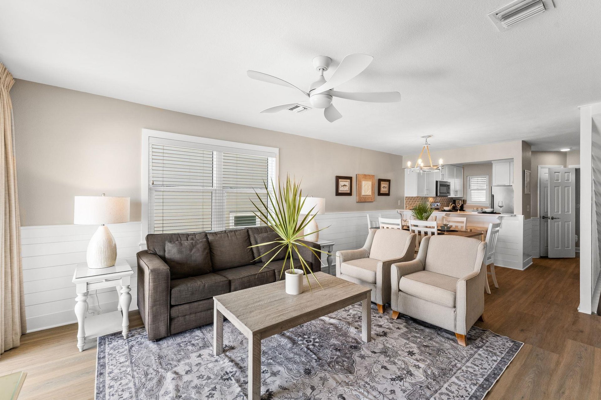 Unwind in the stylish living space with modern furnishings, ceiling fan comfort, and an open layout connecting to the fully equipped kitchen.