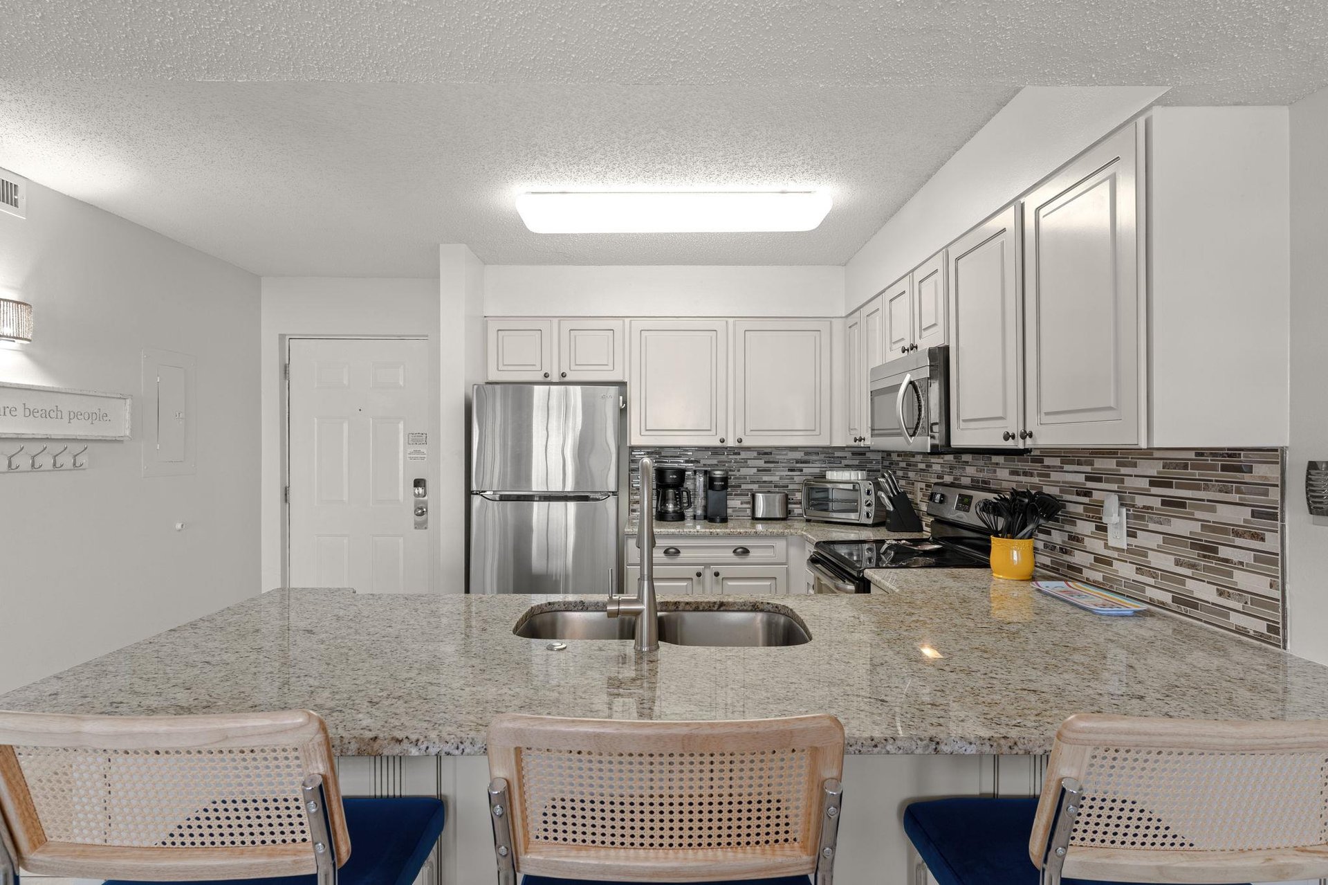 The fully equipped kitchen features granite counters, stainless appliances, and a breakfast bar