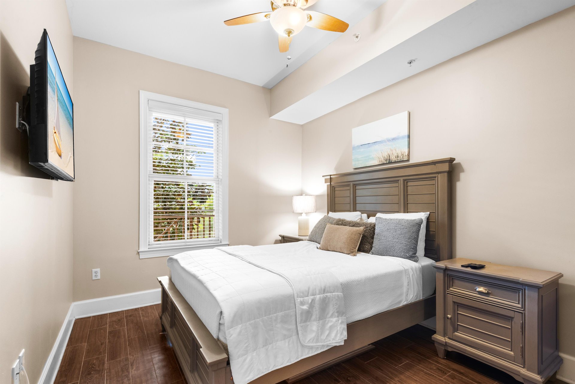 Rest peacefully in this queen size bedroom with crisp linens, warm wood furnishings, and gentle natural light streaming through the window.