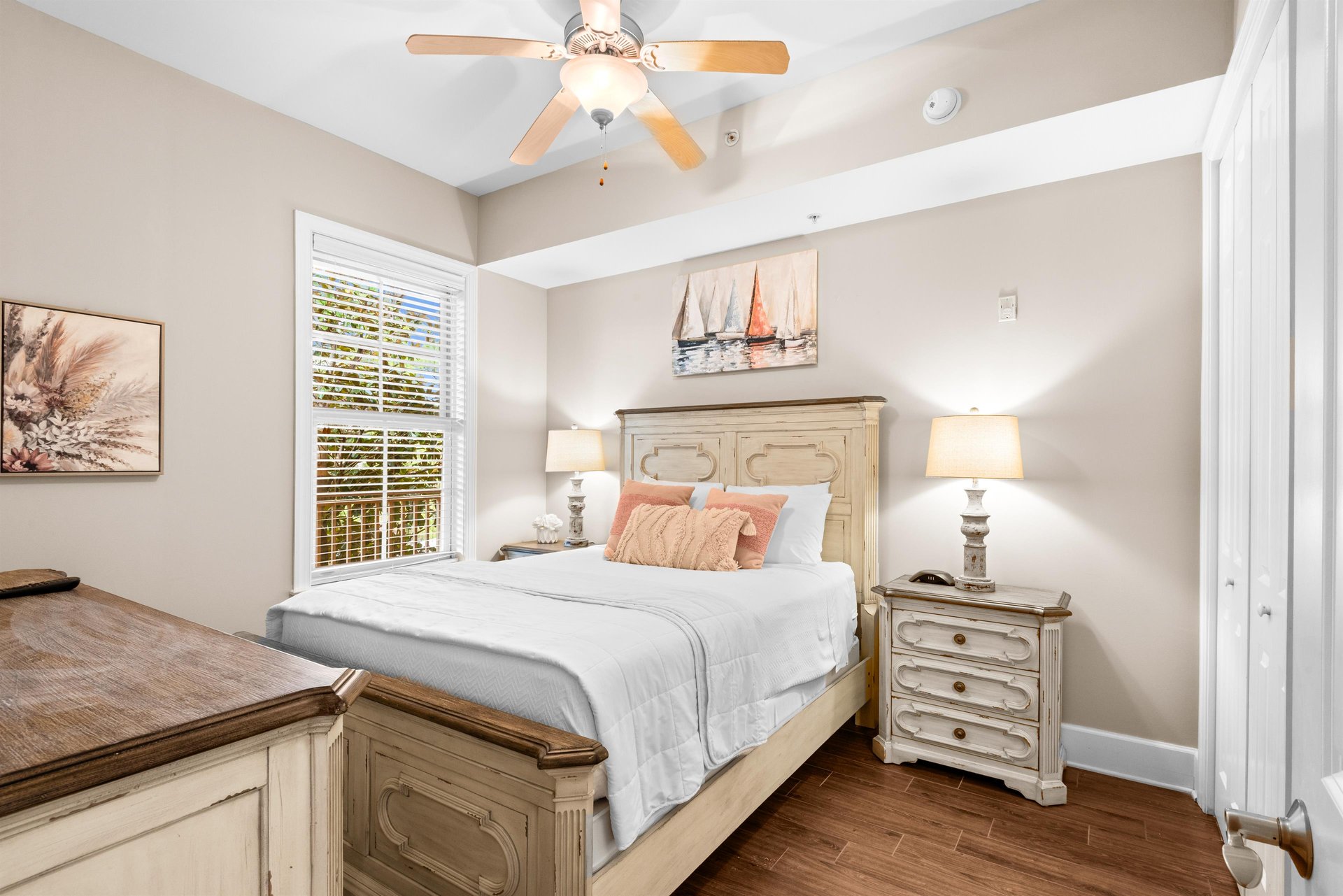 Recharge in this queen bedroom with warm coastal décor, gentle ceiling fan breeze, and coastal artwork.