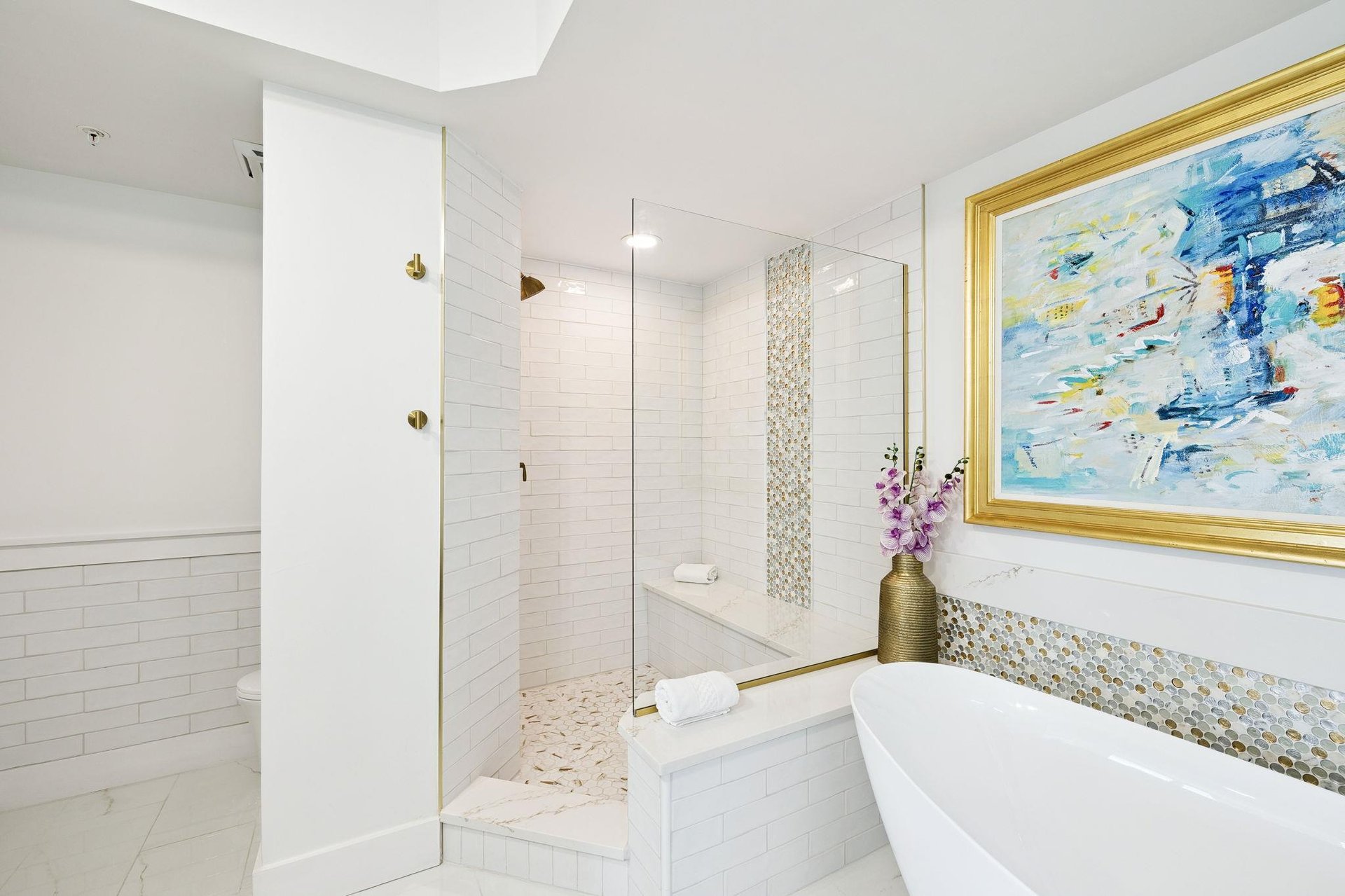 Soak in your elegant marble bathroom featuring a luxurious soaking tub and glassenclosed shower with gold accents.