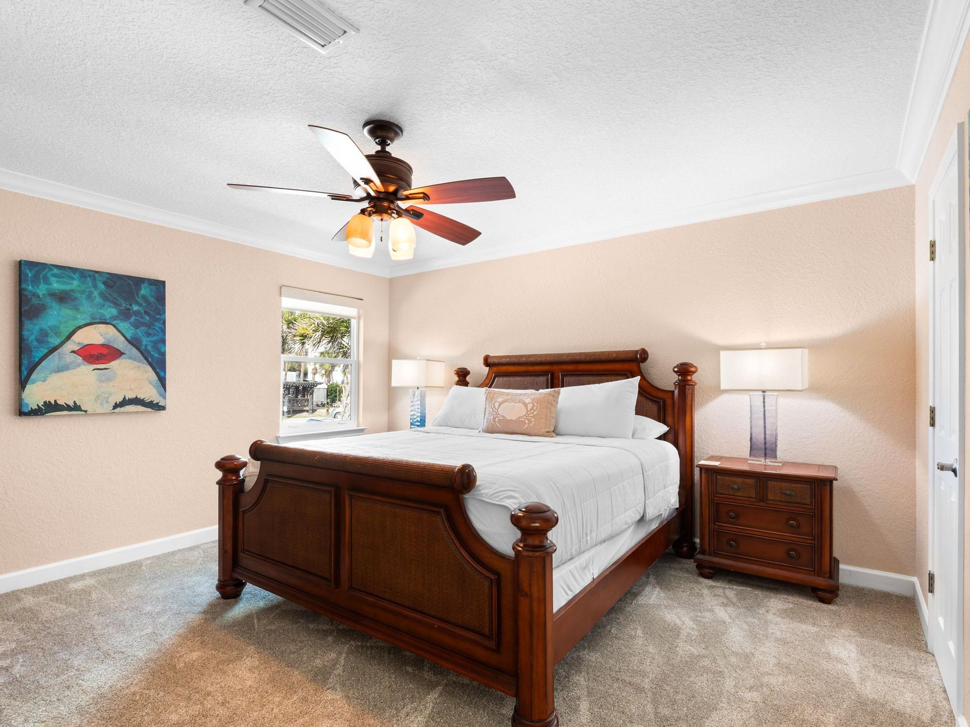 Sink into this cozy bedroom featuring a rich wooden bed, soft linens, and gentle ceiling fan to keep you comfortable all night.