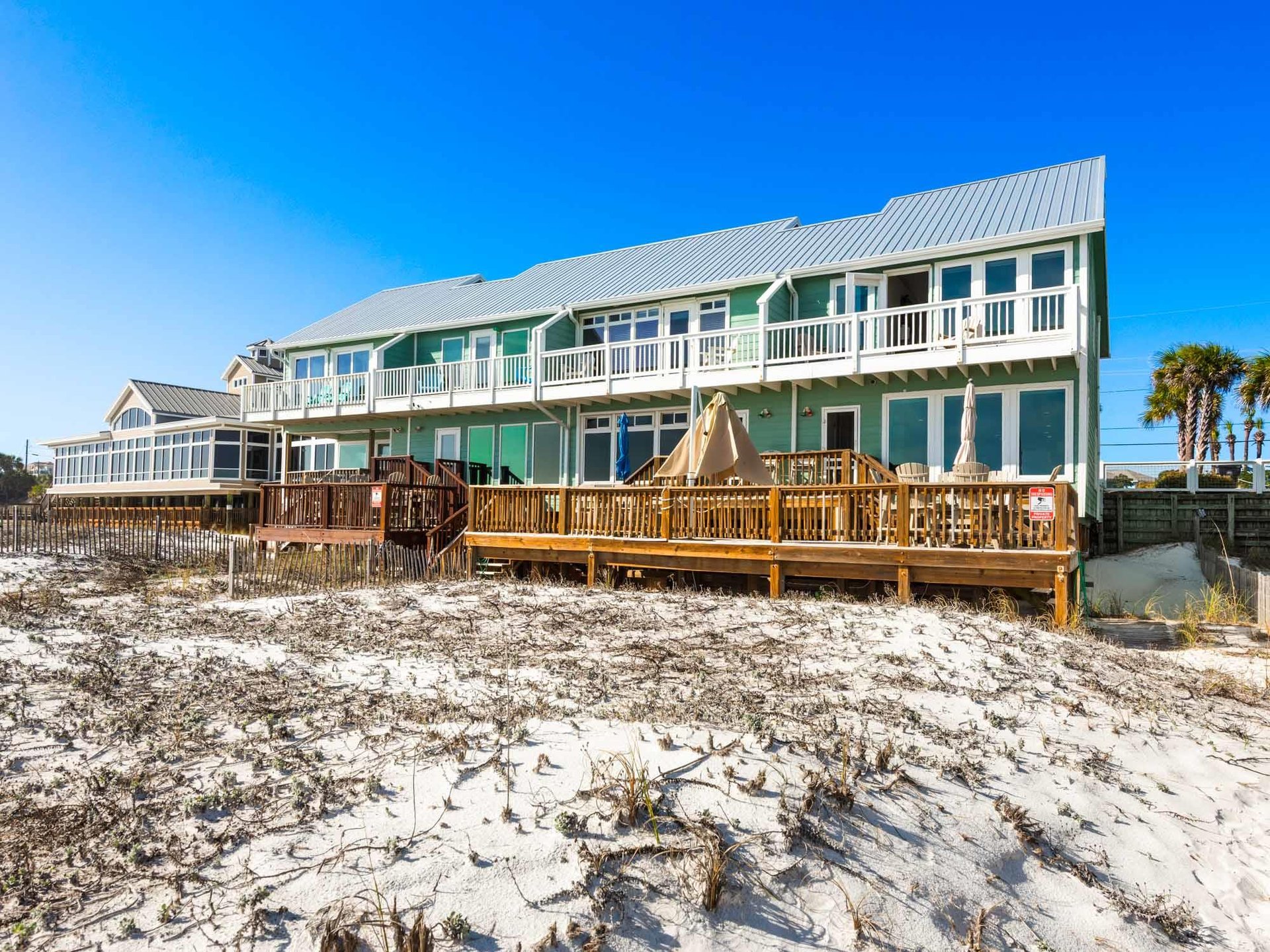Beachfront property with elevated decks, featuring direct beach access and coastal views.