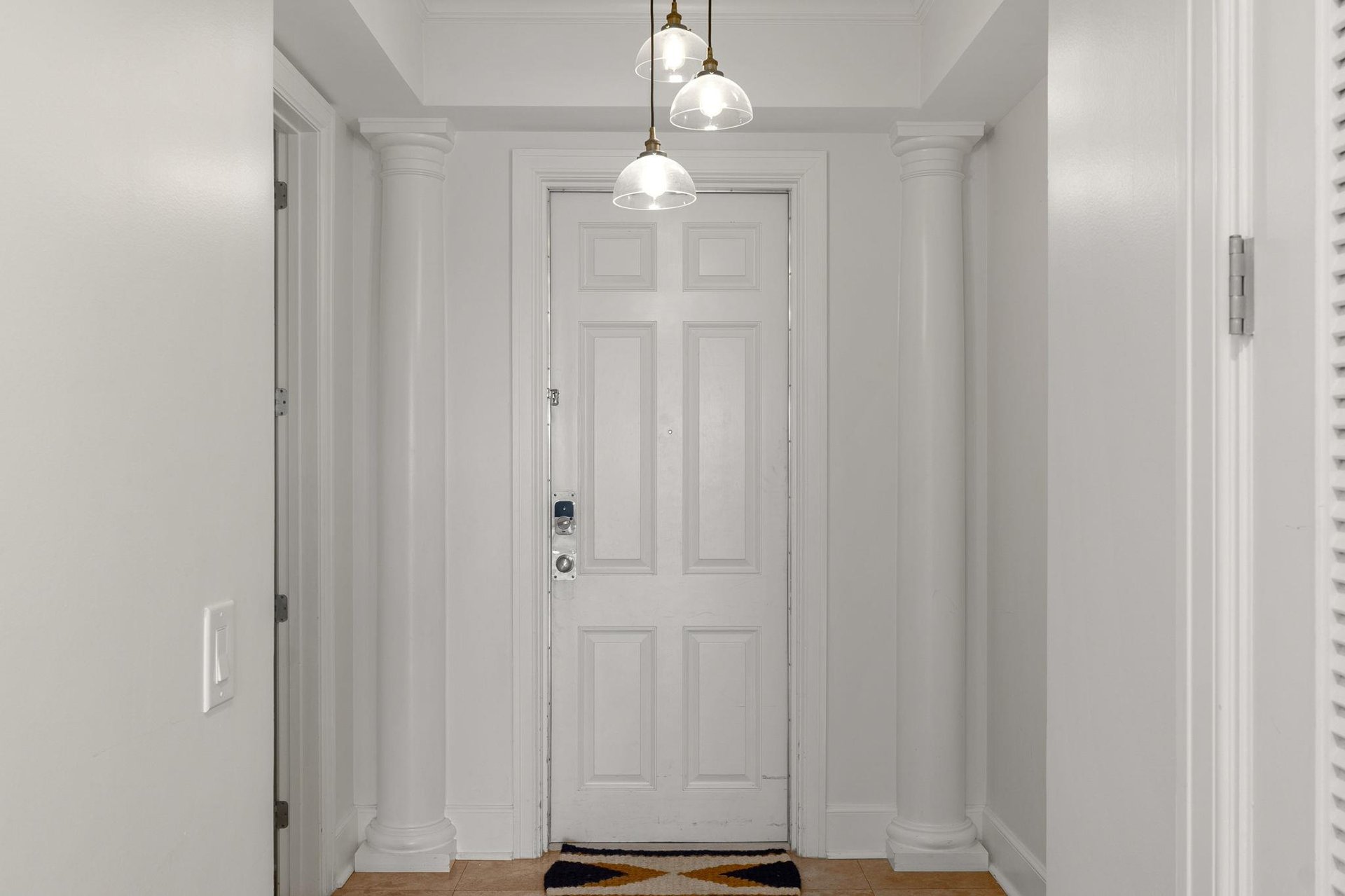 Step into your elegant entryway with soaring columns, warm pendant lighting, and classic details that welcome you home.