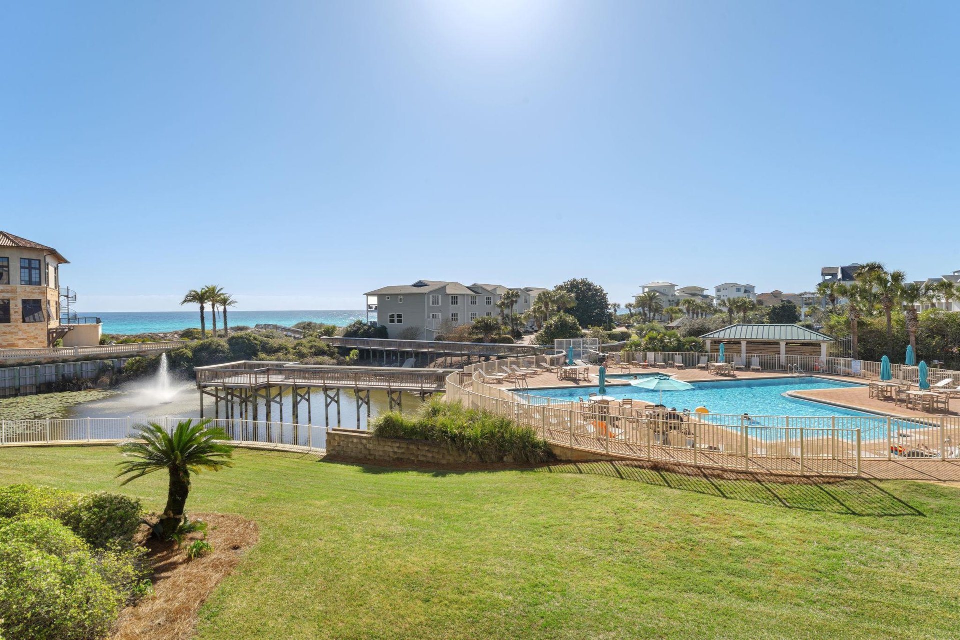 Stunning beachfront resort community with sparkling pool facilities and coastal views. Property buildings nestled among palm trees near pristine shoreline.